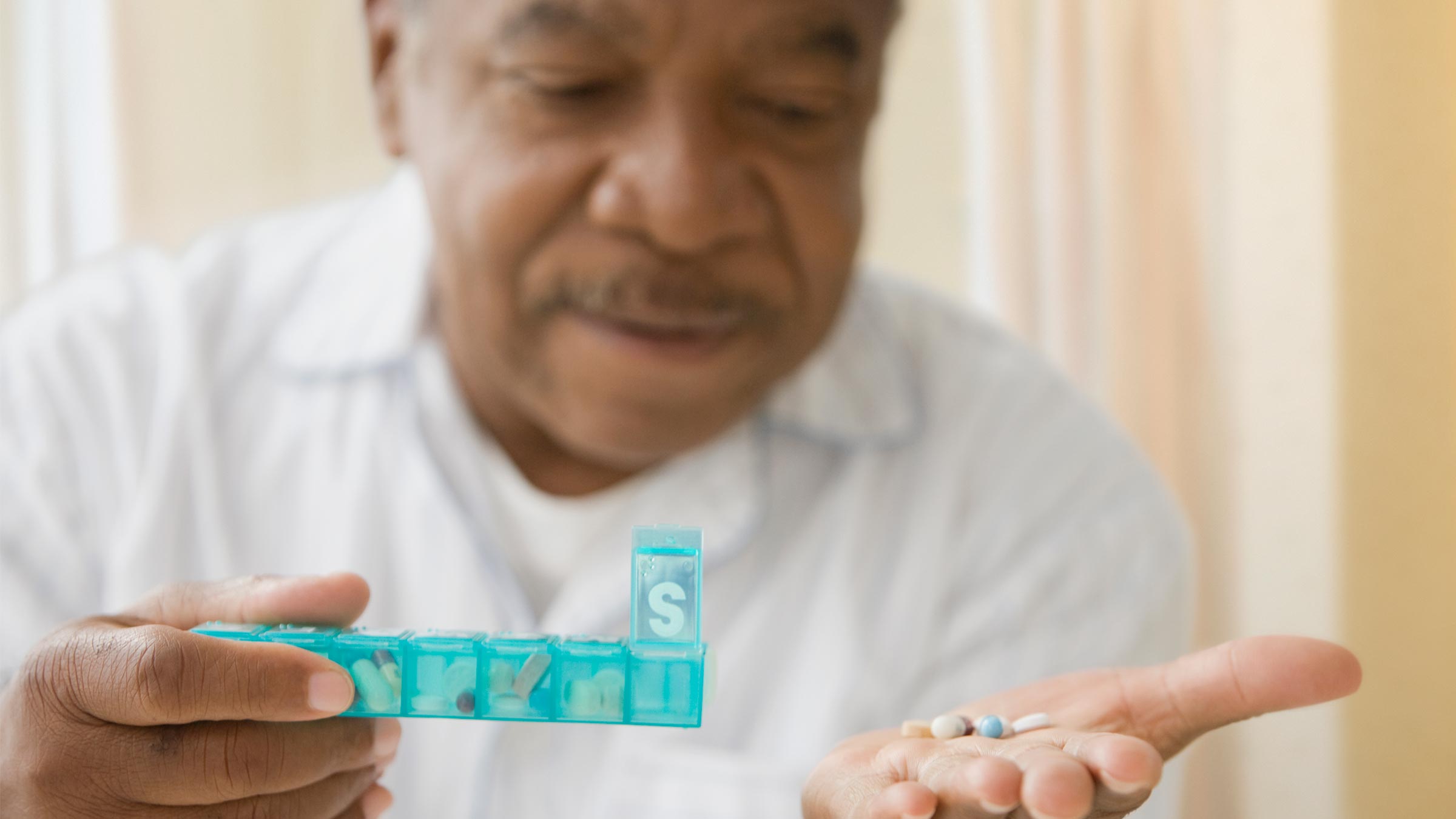 Elderly man holding a handful of pills. 