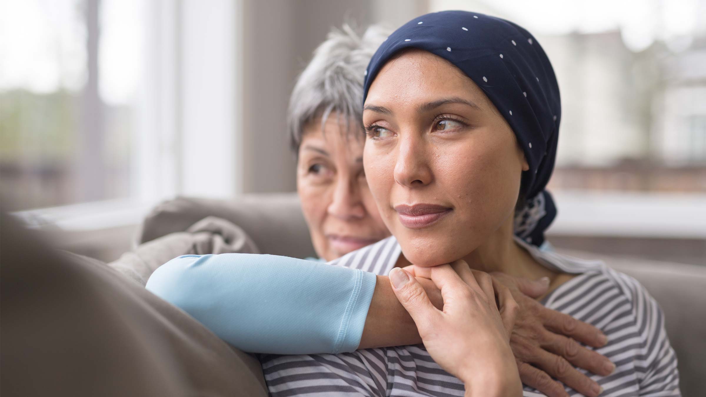Woman wearing headscarf sits on the couch with older woman
