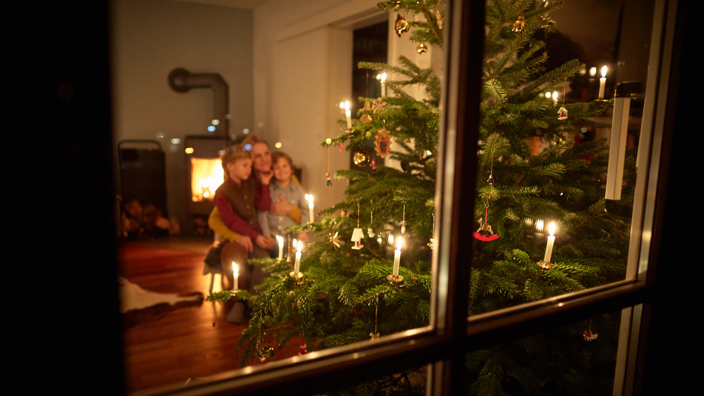 Mother and sons looking at illuminated Christmas tree