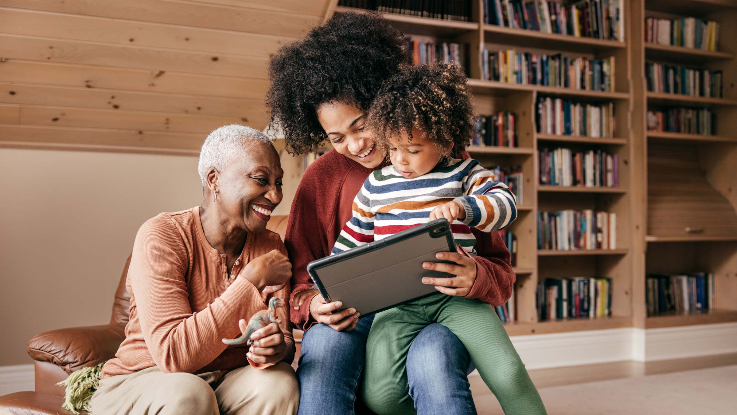 Three generation family sitting with tablet and laughing together