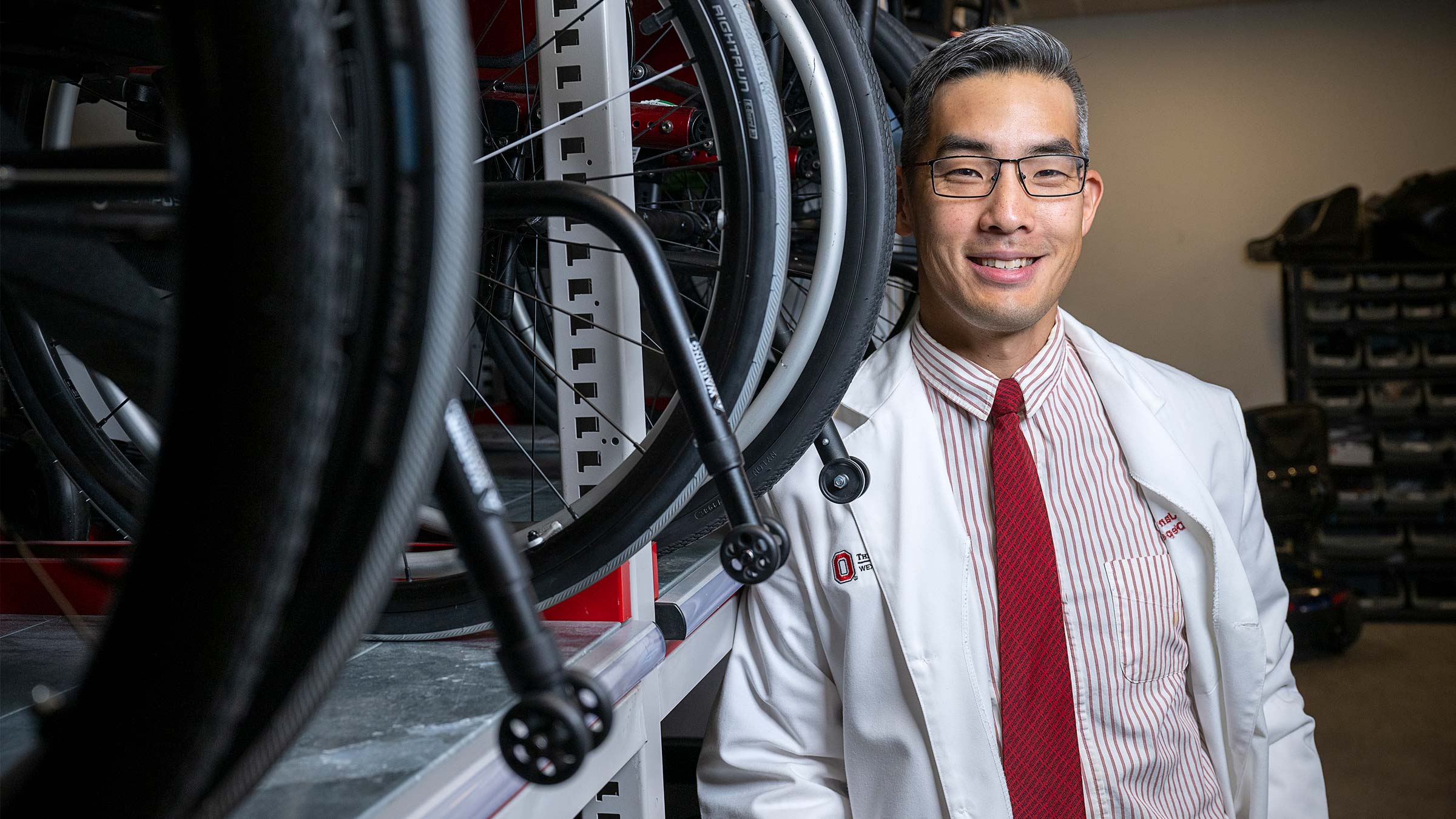 Daniel Kim, MD, standing next to wheelchairs at Ohio State's Assistive Technology Center