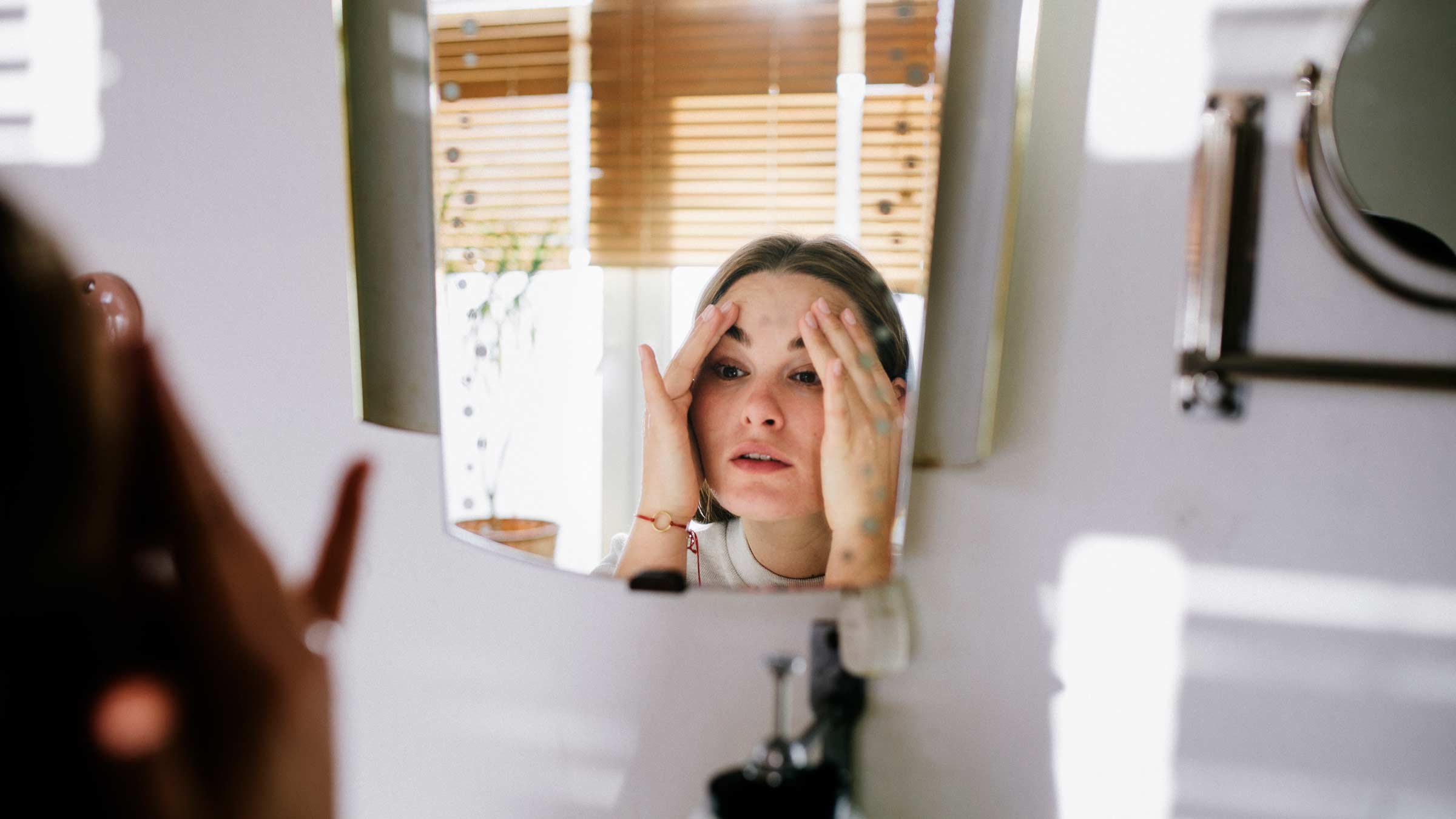 Woman looking in bathroom mirror after cleaning her face