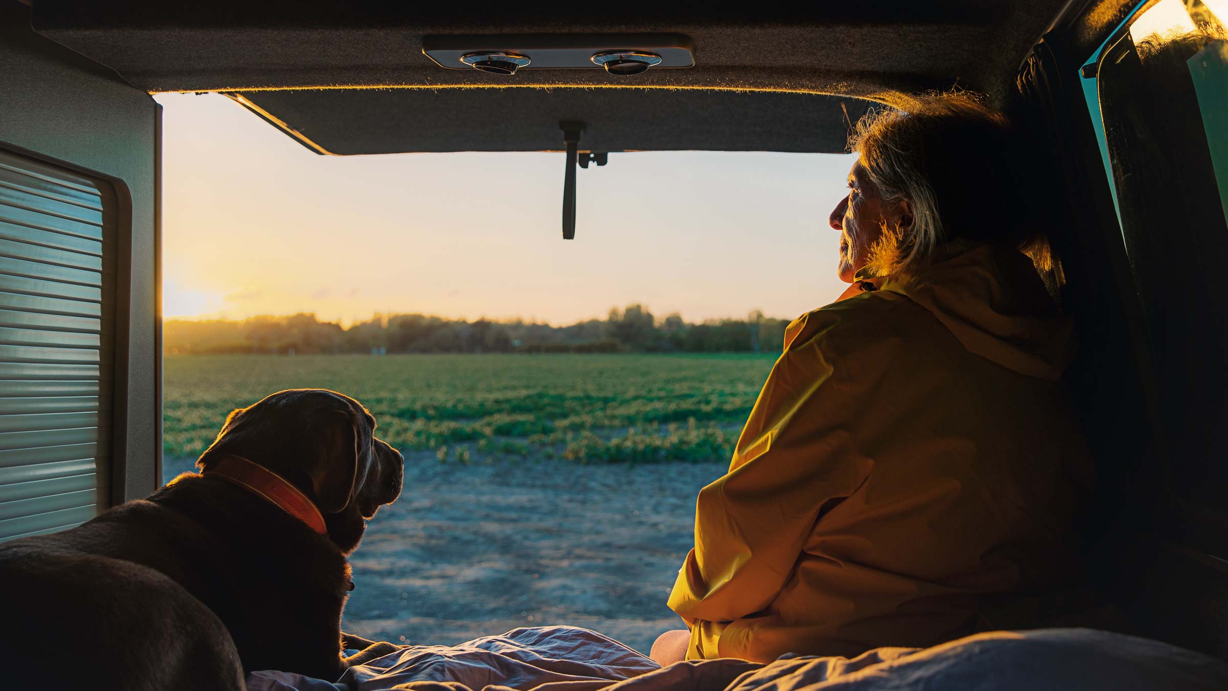 Woman and her pet dog in the back of her campervan