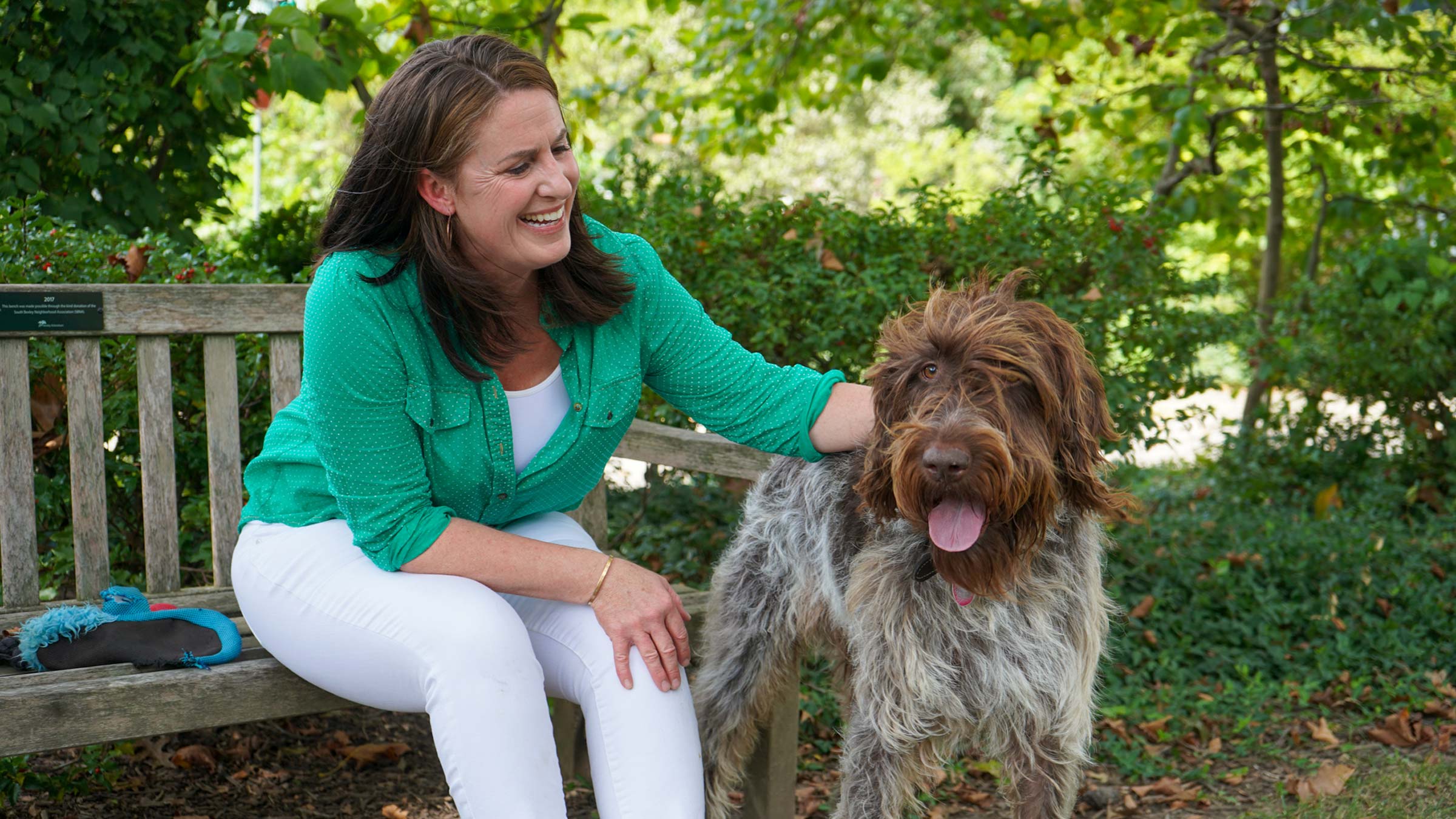 Britt Collier-Gibson sitting on a bench, petting a dog