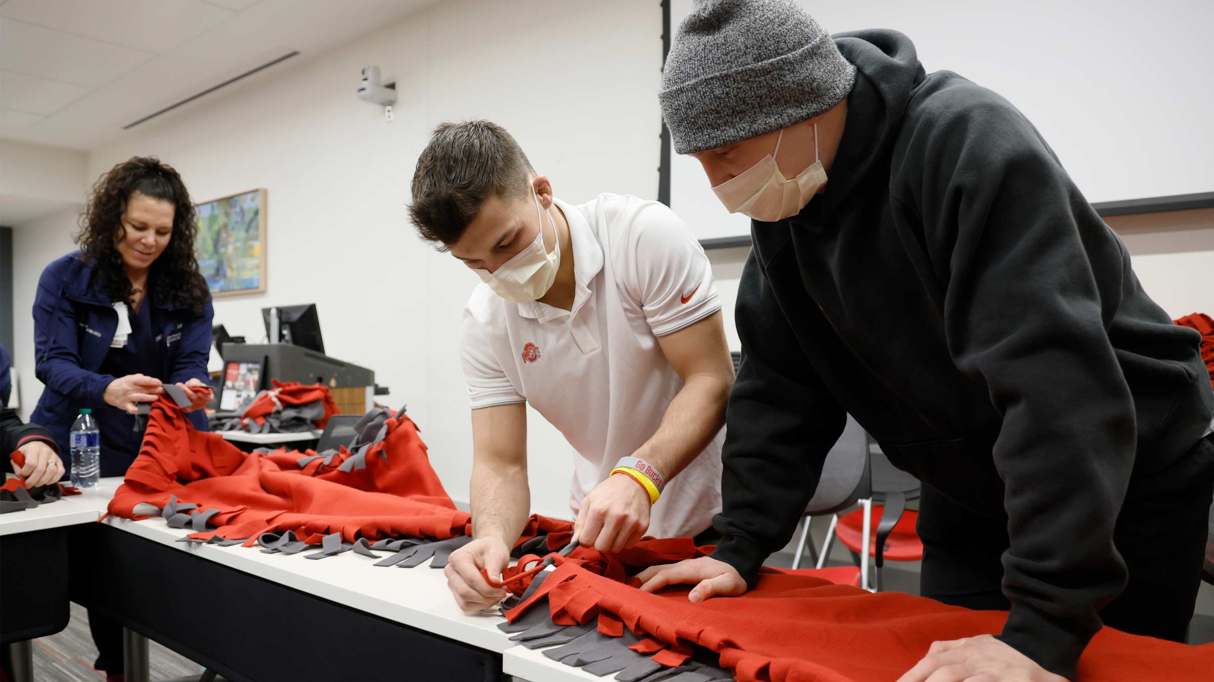 Ohio State University wrestler Nic Bouzakis, center, makes a blanket with fellow wrestler Gavin Hoffman and nurse Andrea Linhart.