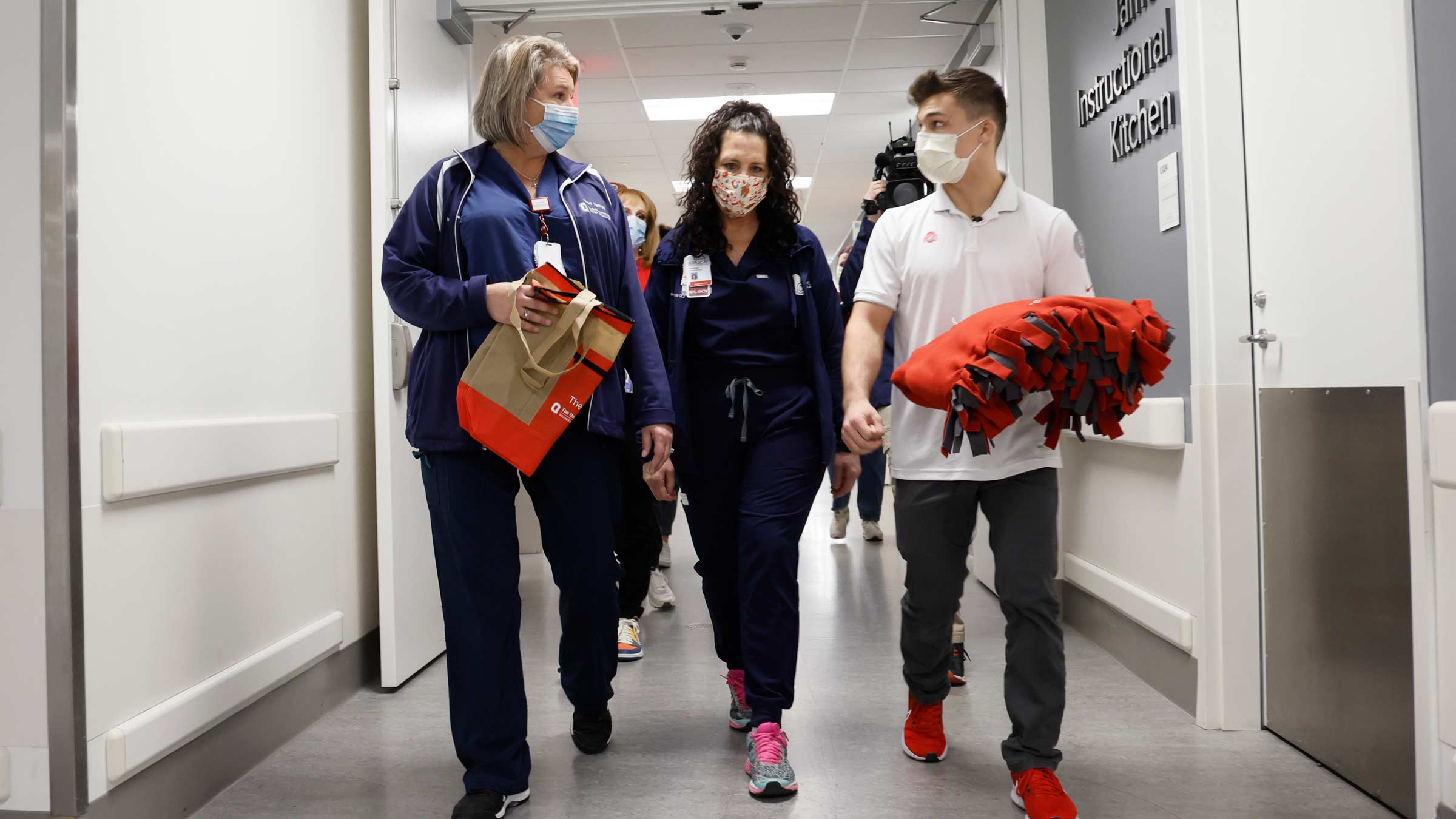 Nic Bouzakis helps cancer nurses Andrea Linhart and Christina Miller deliver completed blankets to chemotherapy patients.