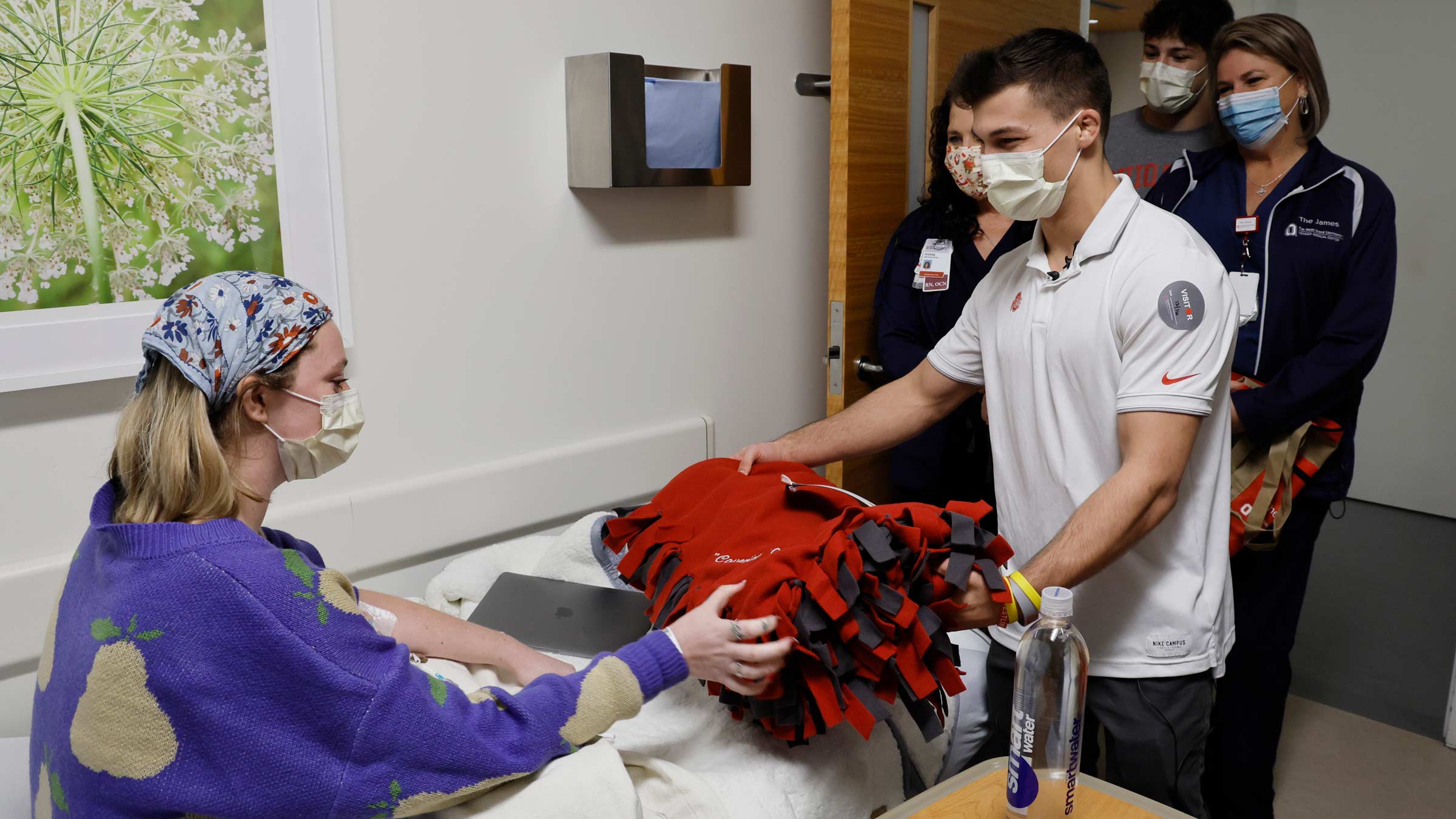 Nic Bouzakis, accompanied by cancer nurses Andrea Linhart and Christina Milller delivers a blanket to a cancer patient.