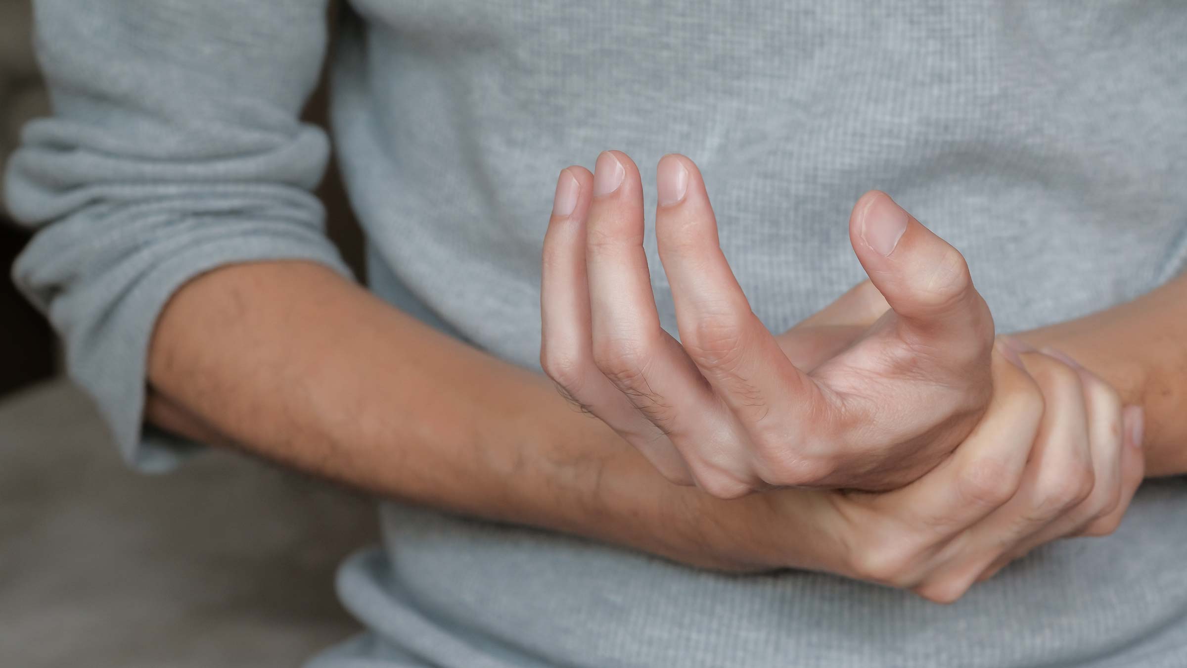 A person with an autoimmune disease clutching their hand