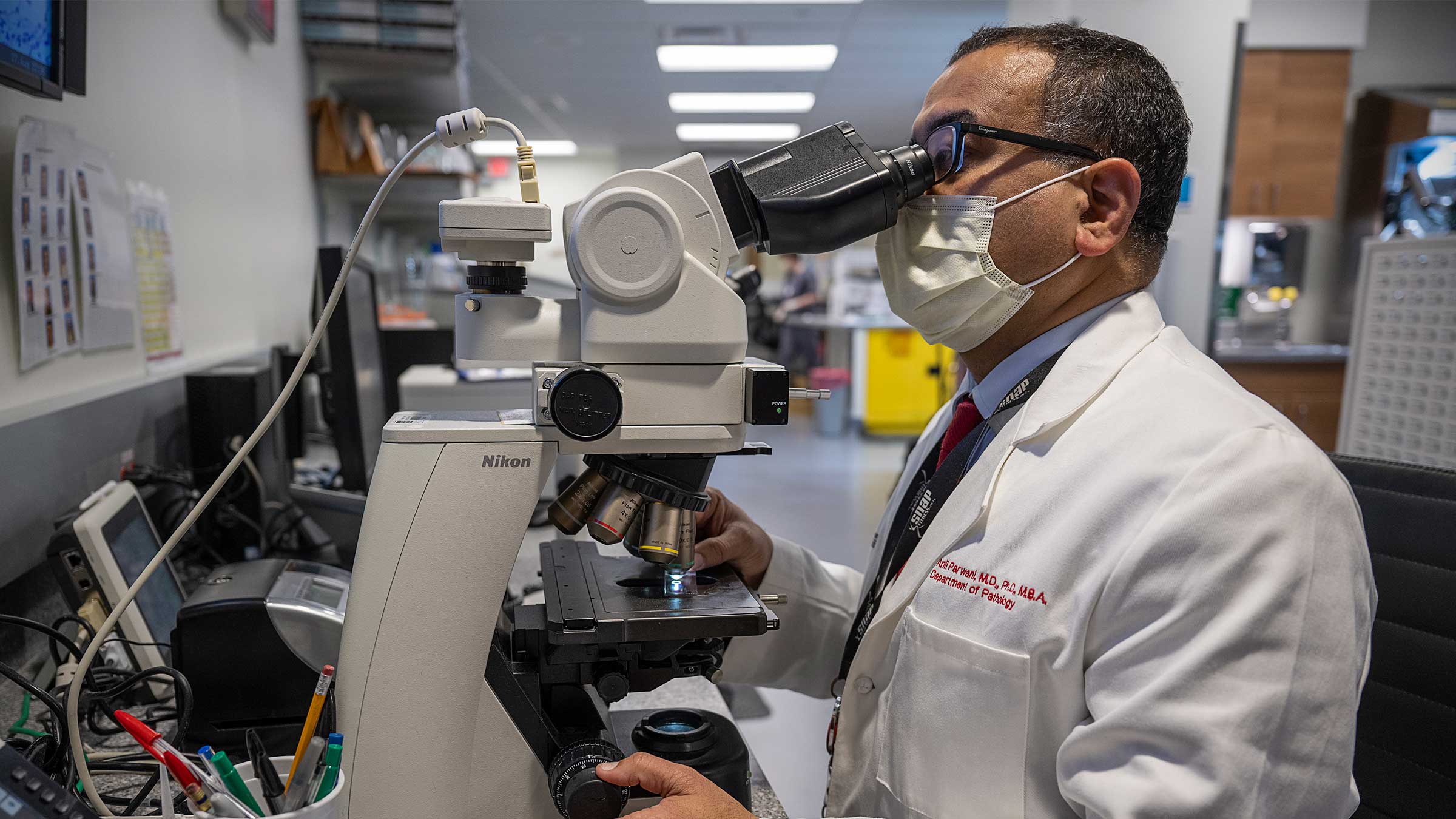 Dr. Anil Parwani looking at cancer cells under a microscope