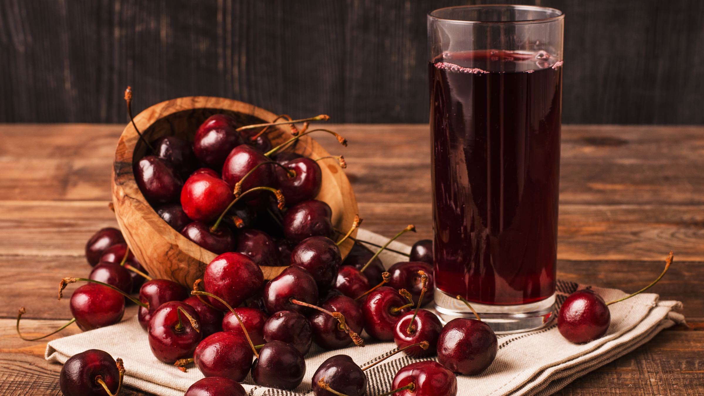 Ripe cherries surrounding a glass of cherry juice