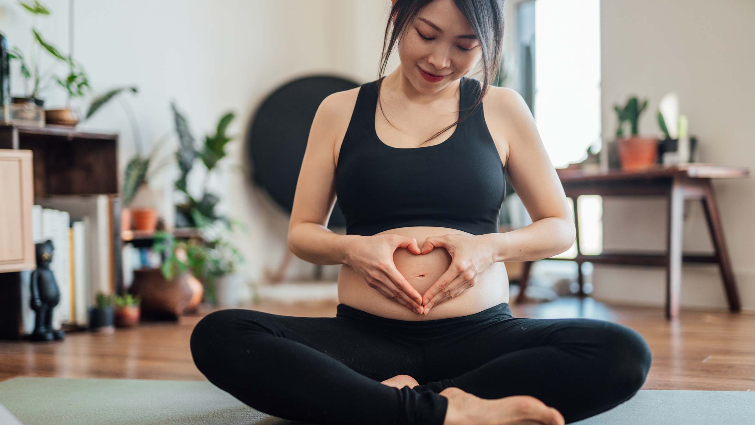 Pregnant woman forming a heart shape with her hands over her pregnant belly