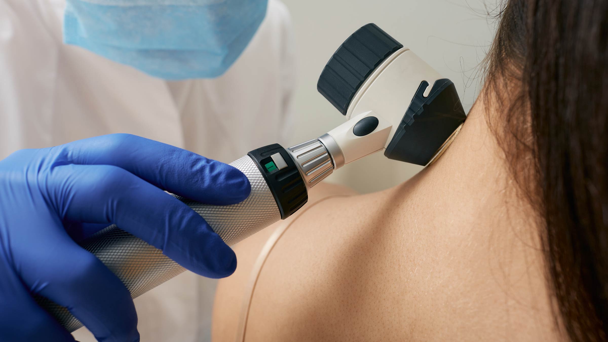 medical professional using a tool to view a skin tag on a woman's neck close up