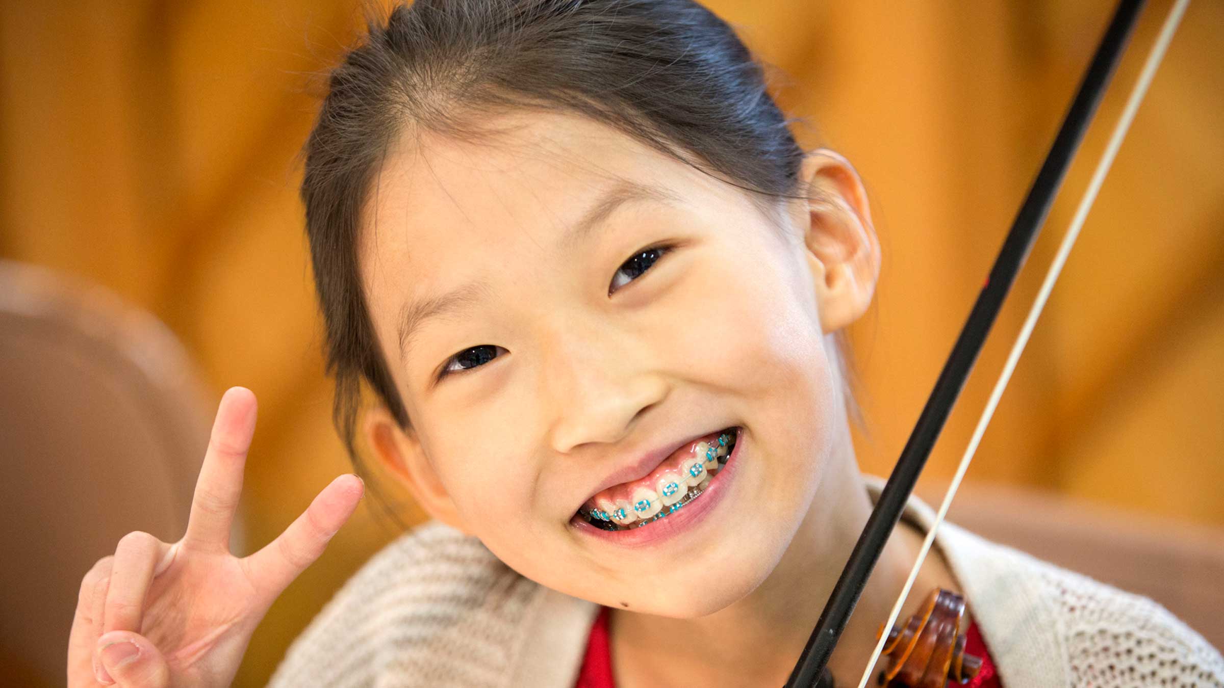 Asian girl smiling with braces and holding a violin
