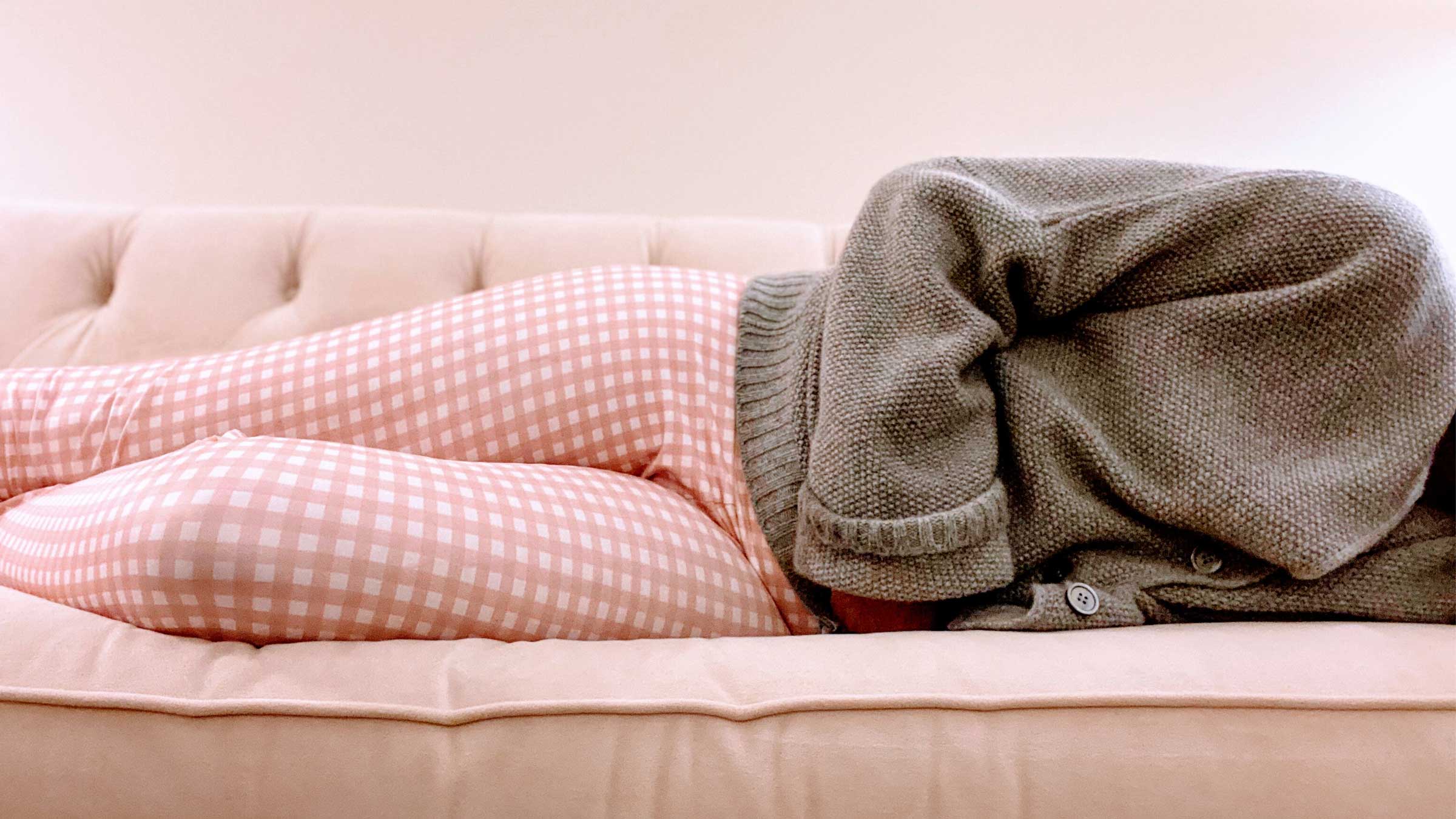 A woman sick with a norovirus laying on a couch. 