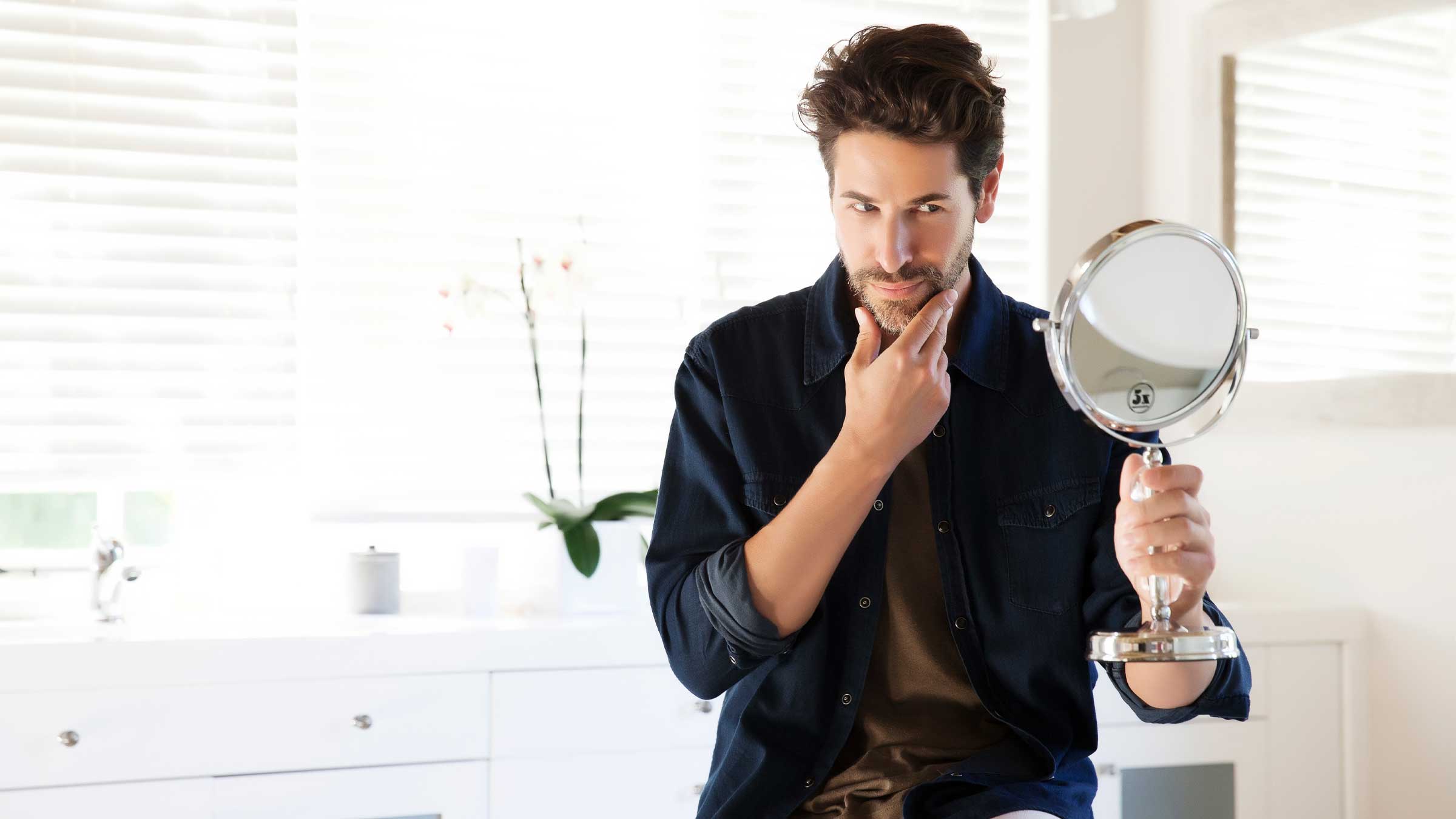 Man looking at his face in the mirror.