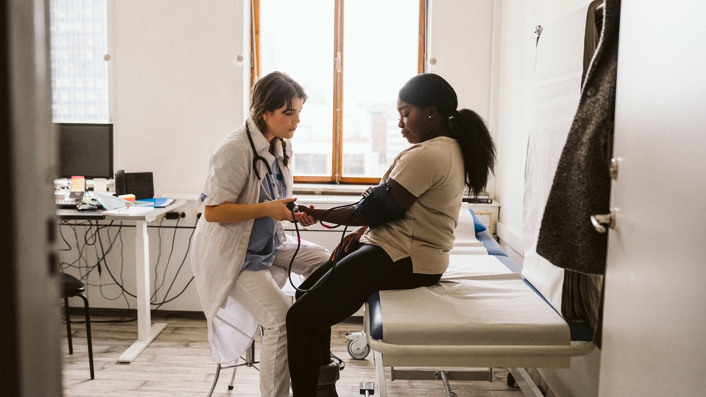 Female health care worker measuring patient's blood pressure in medical clinic