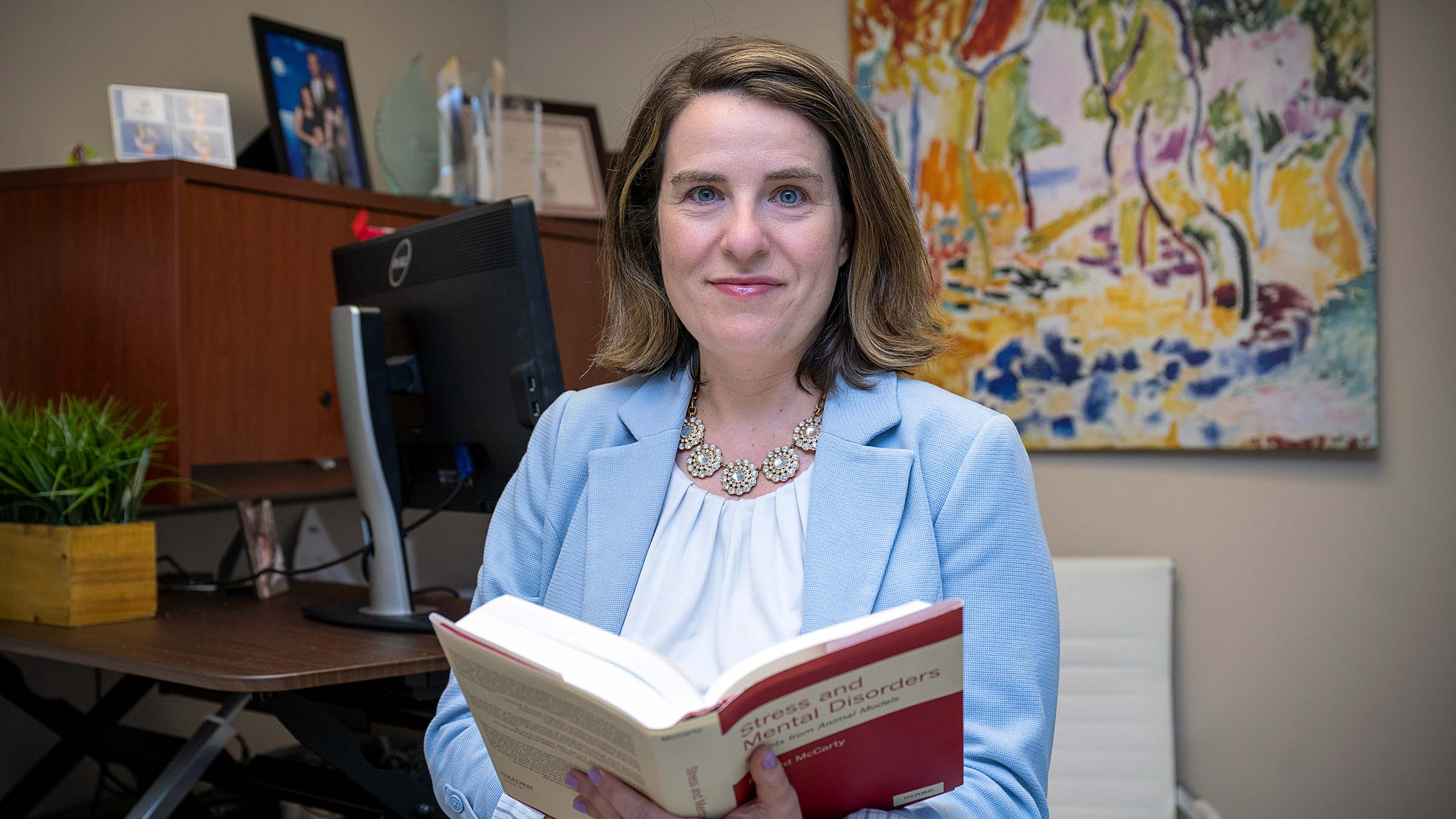 Dr. Tamar Gur in her office at Ohio State holding a clinical textbook 