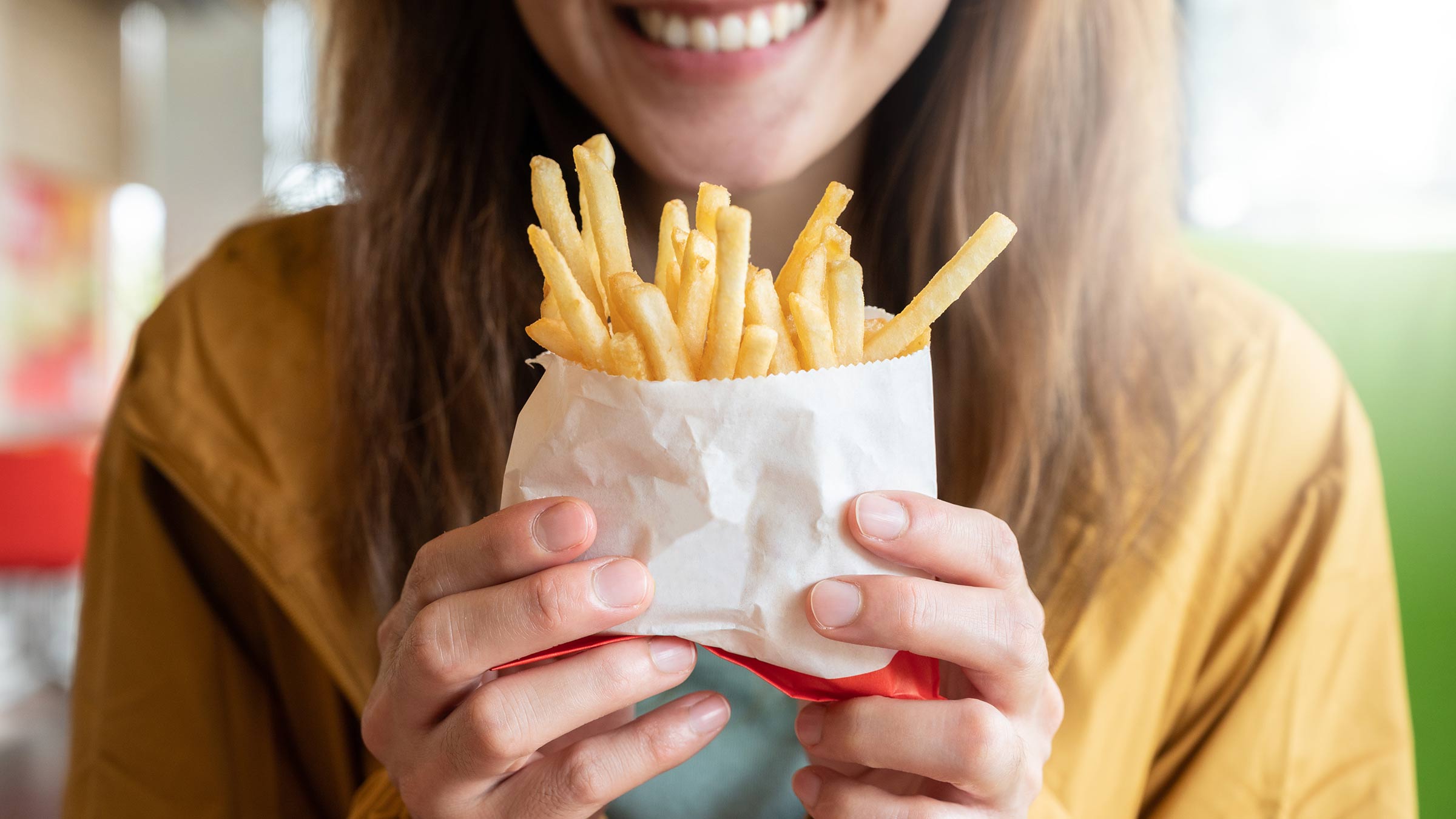 Close-up of woman smiling and holding French fries