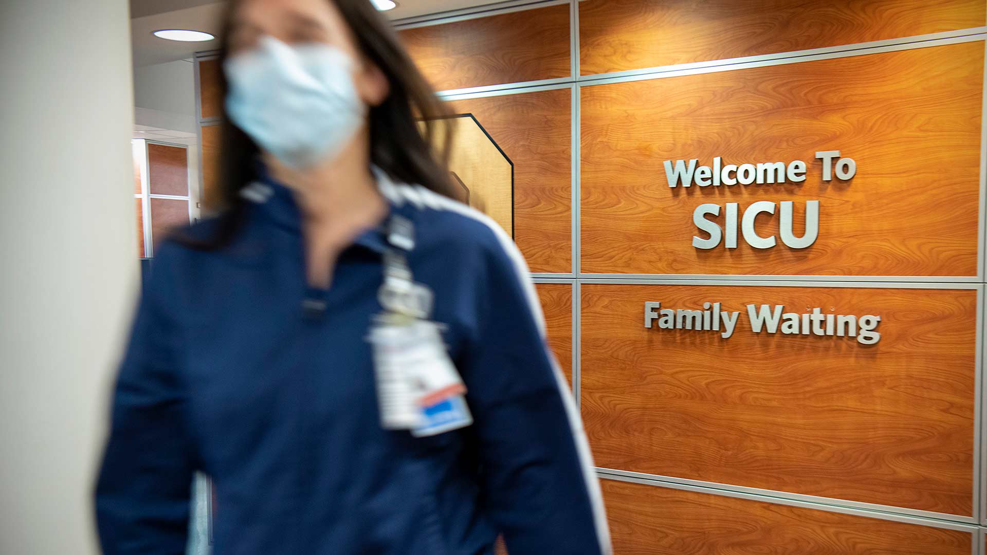 A nurse walking past a "Welcome to SICU" sign