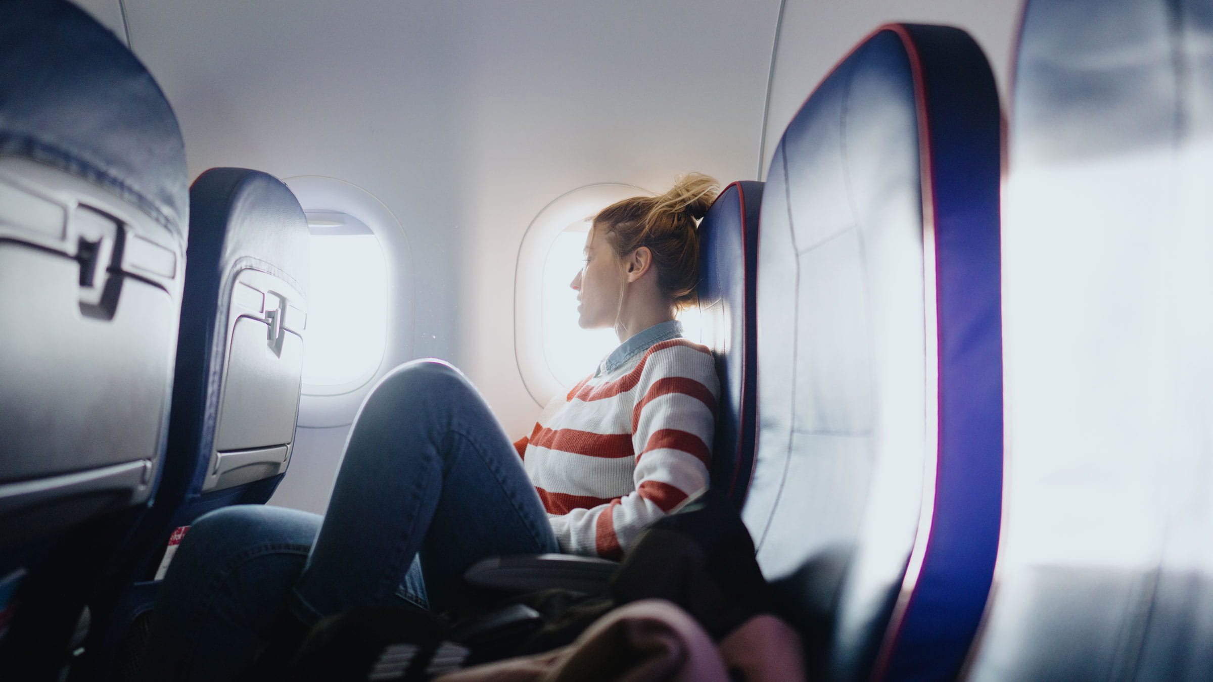 Young woman looking out the window of a plane