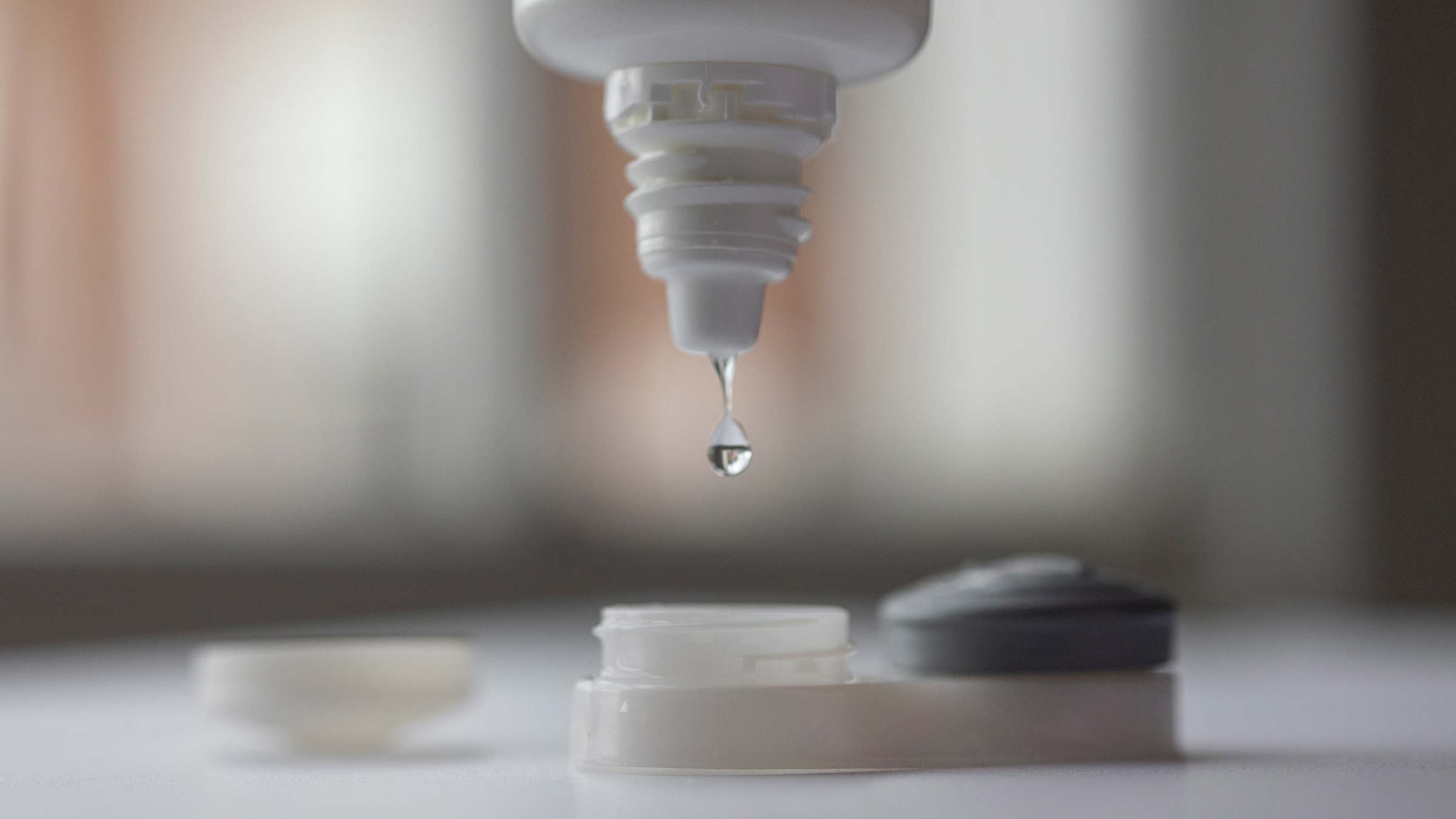 Close up of a saline dropping into a contact lens case