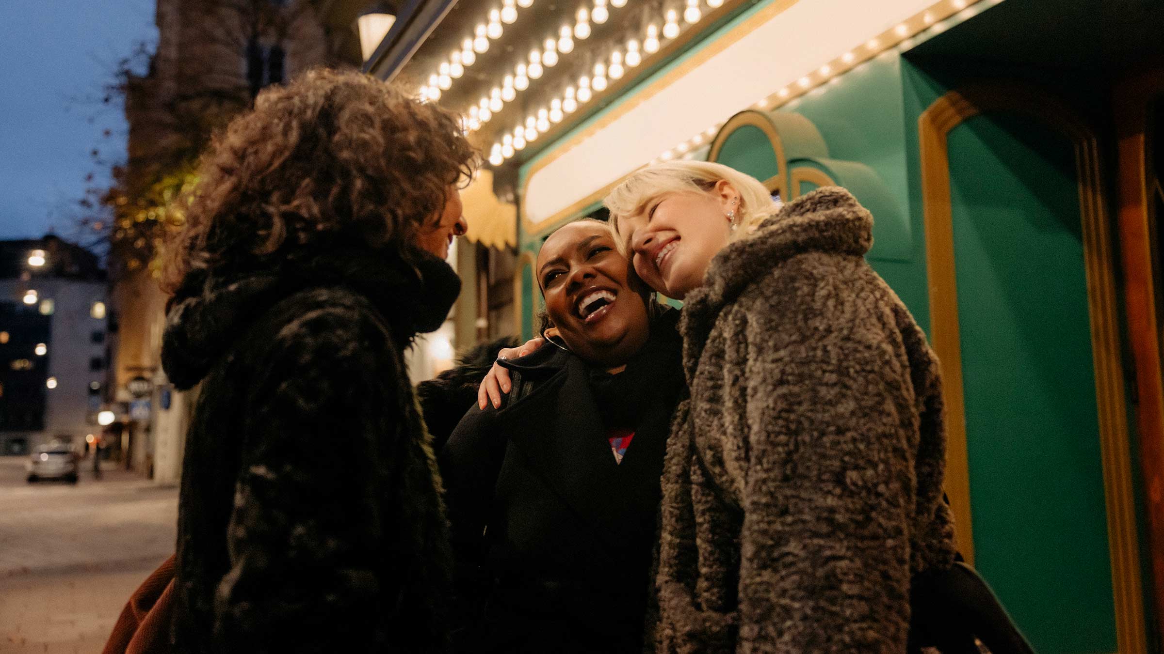Three female friends hugging outside a theater