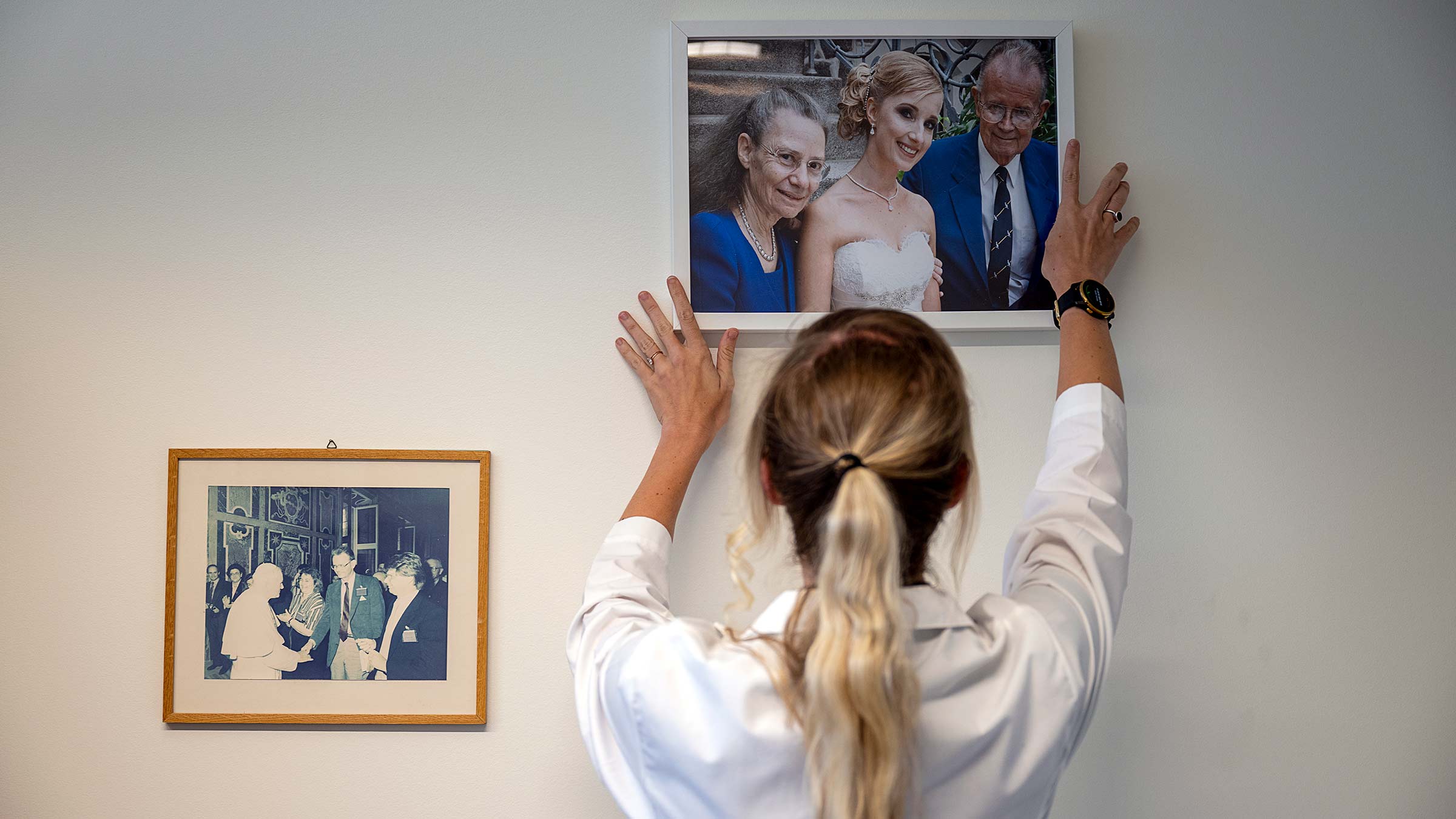 Ann-Kathrin Eisfeld is adjusting a photo on the wall picturing her and her mentors at her wedding