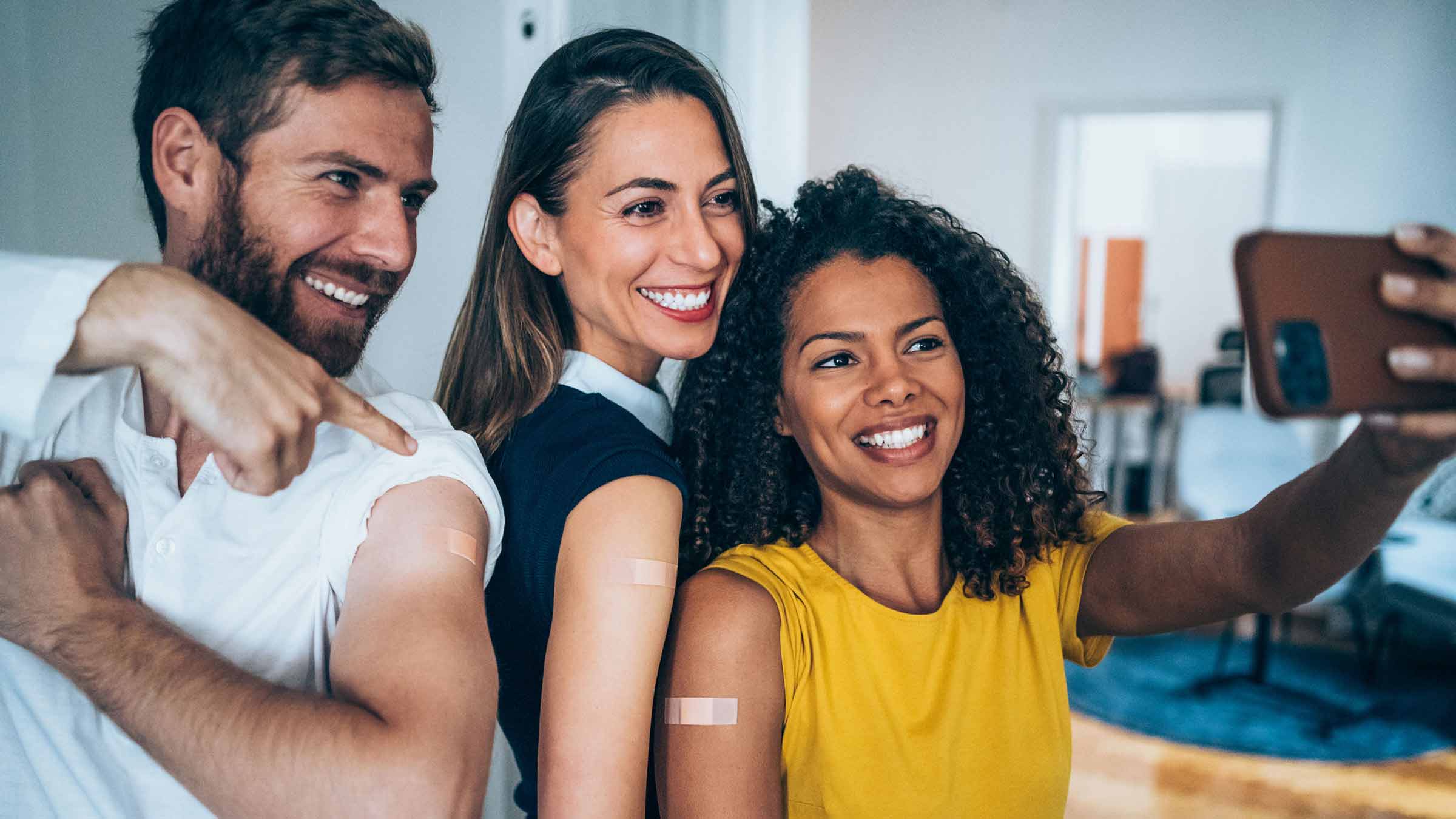 Friends taking a photo proudly showing their arms after getting vaccinated.