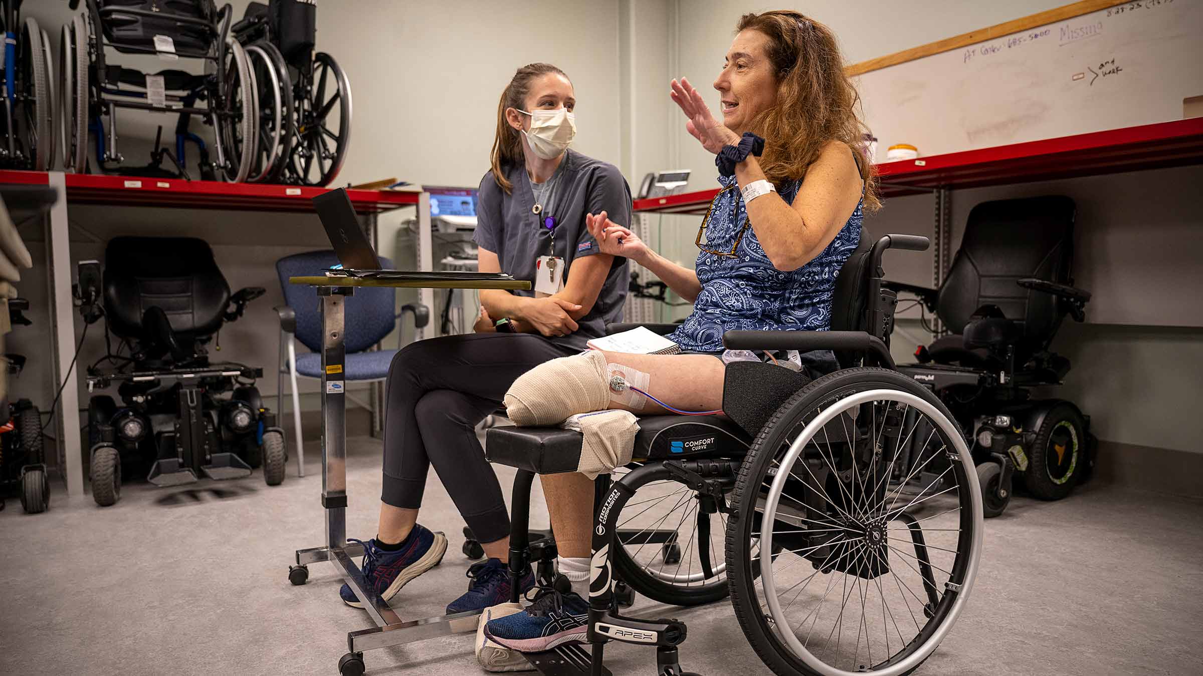 A patient in a wheelchair talking to a nurse