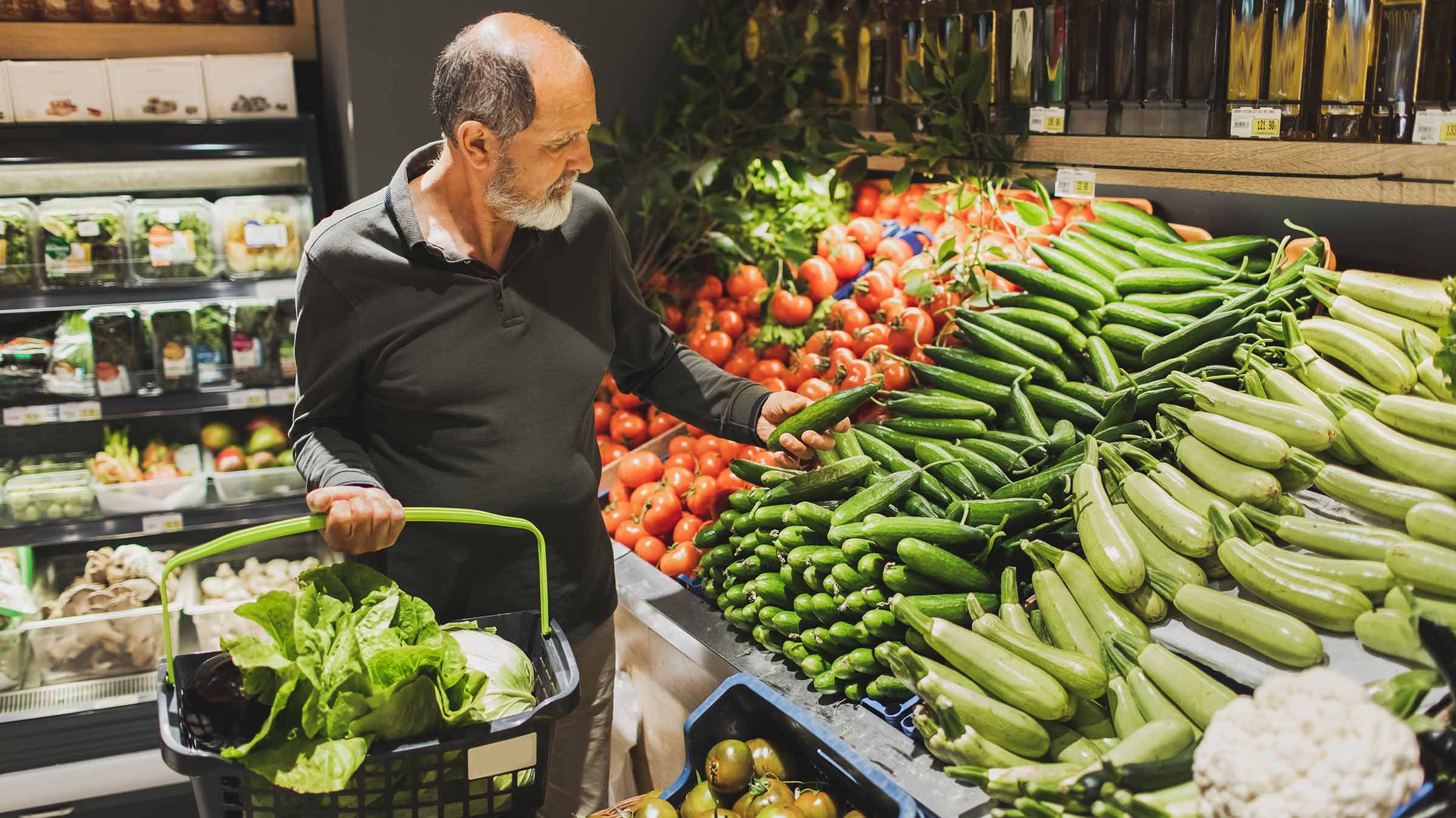 A man picking vegetables in a grocery store