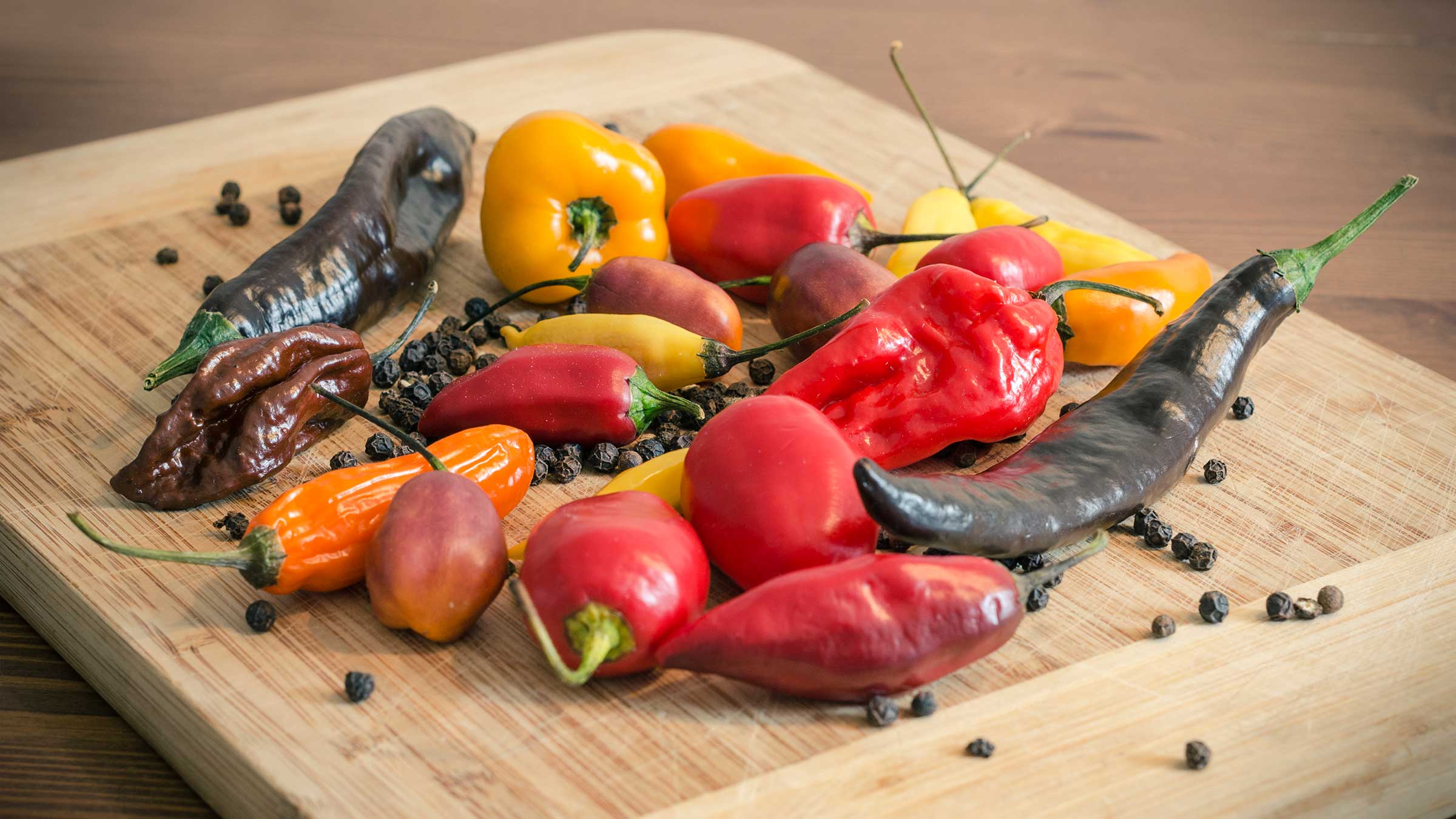 Hot chili peppers with peppercorns on a wooden board