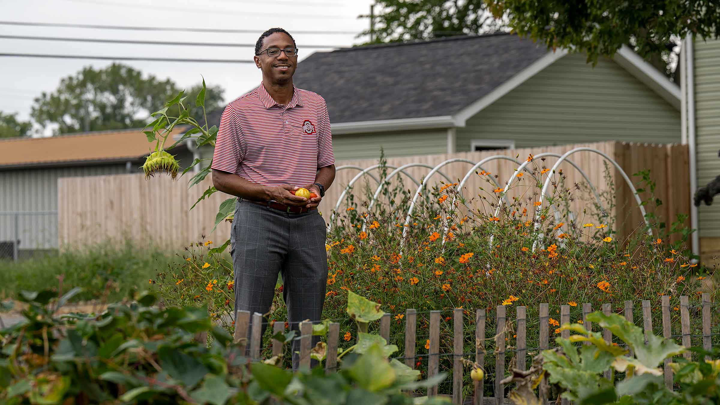 Dr. Joseph standing in a garden holding tomatoes
