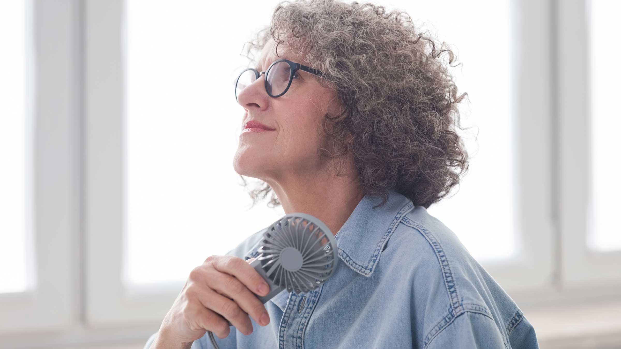 Older woman with a cooling fan in her hands