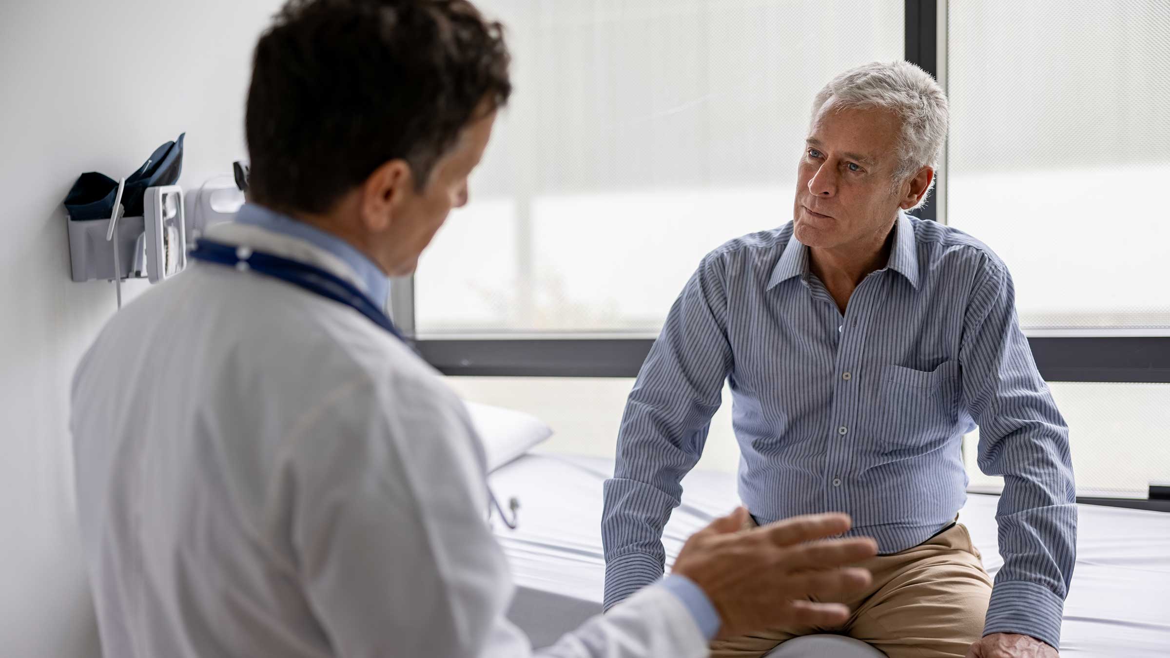 A doctor talks to a patient in an exam room