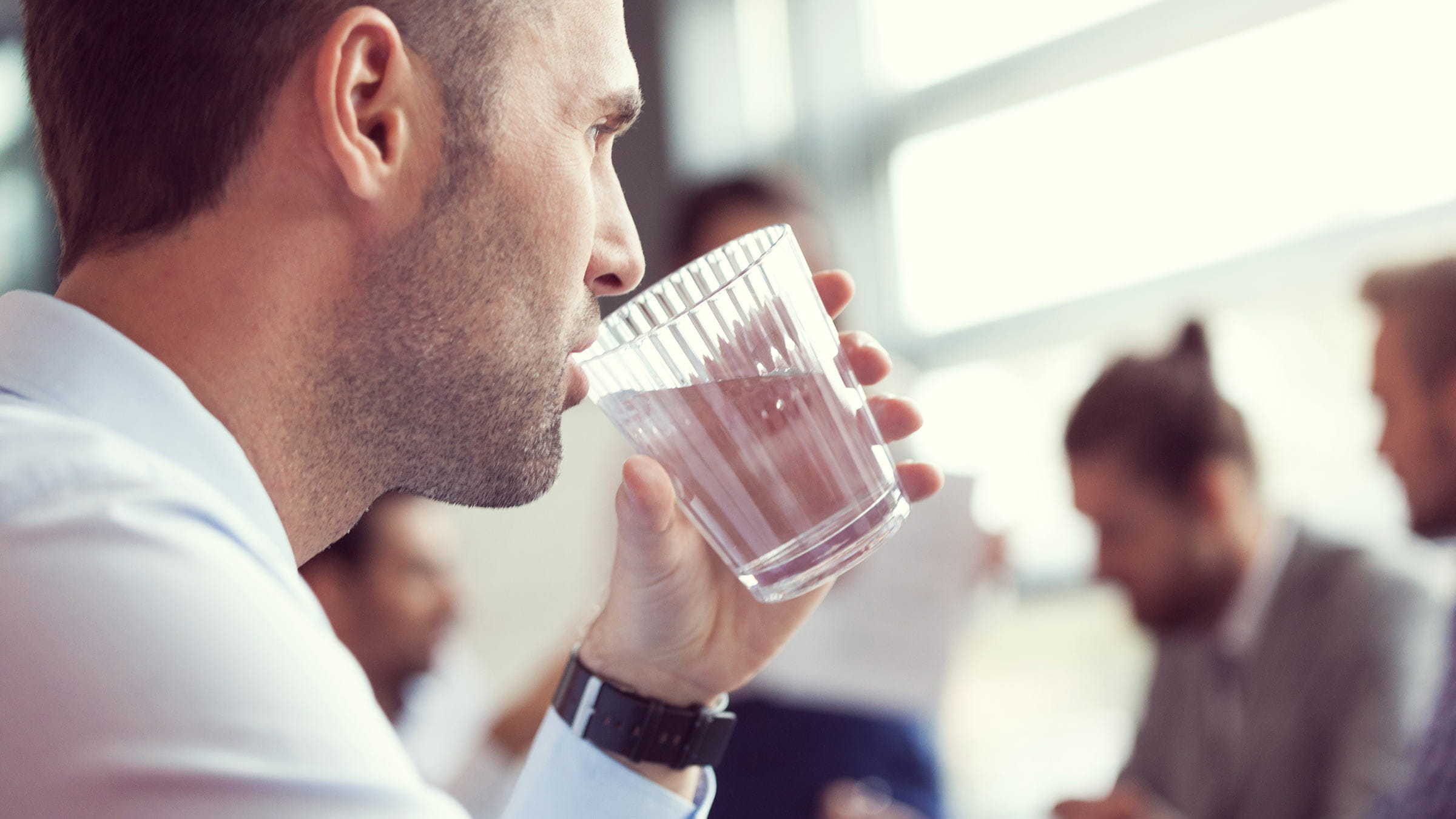 A man drinking a glass of water in a conference room