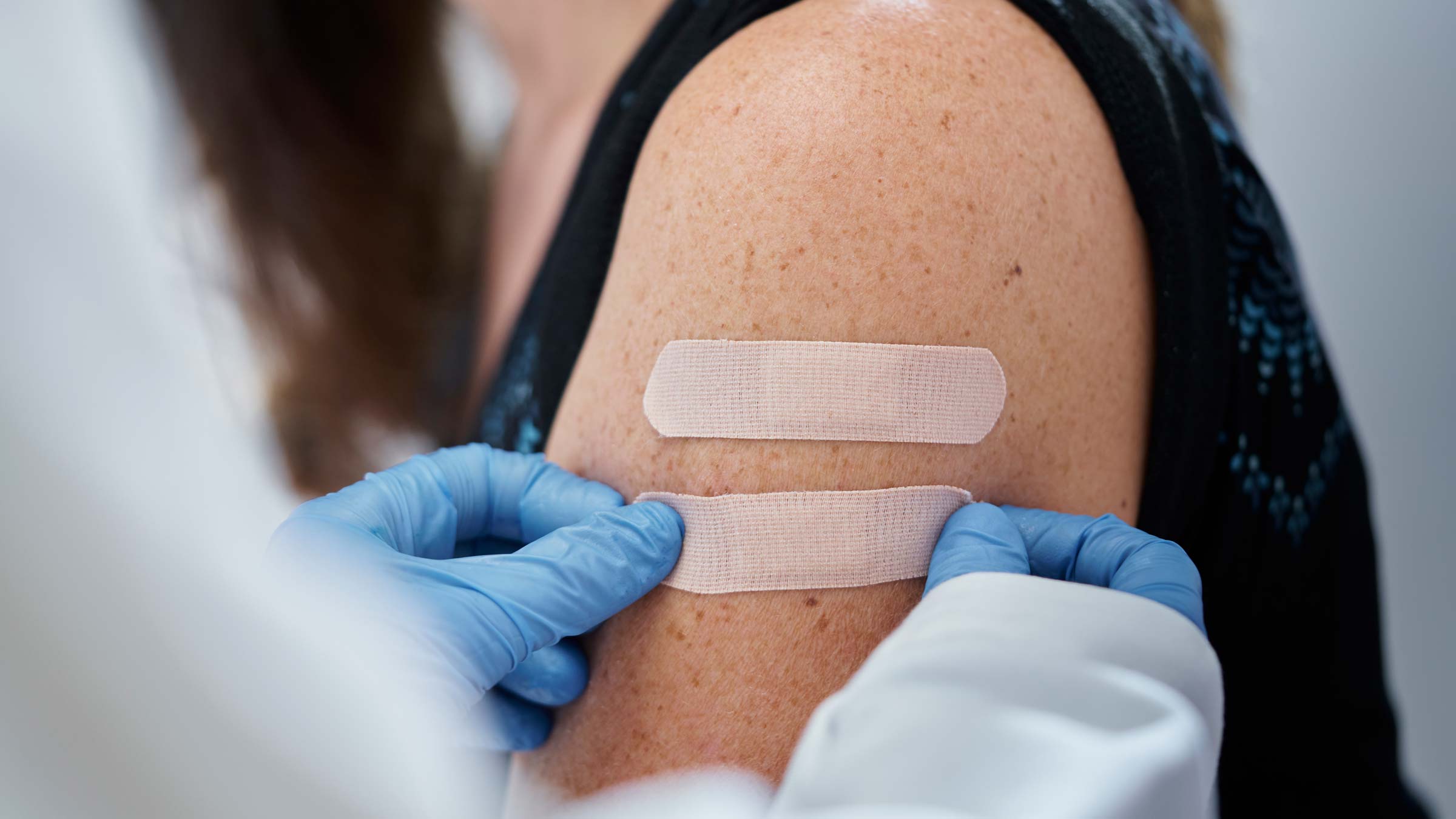 A doctor putting a band aid on a patient’s arm after they received a flu vaccine
