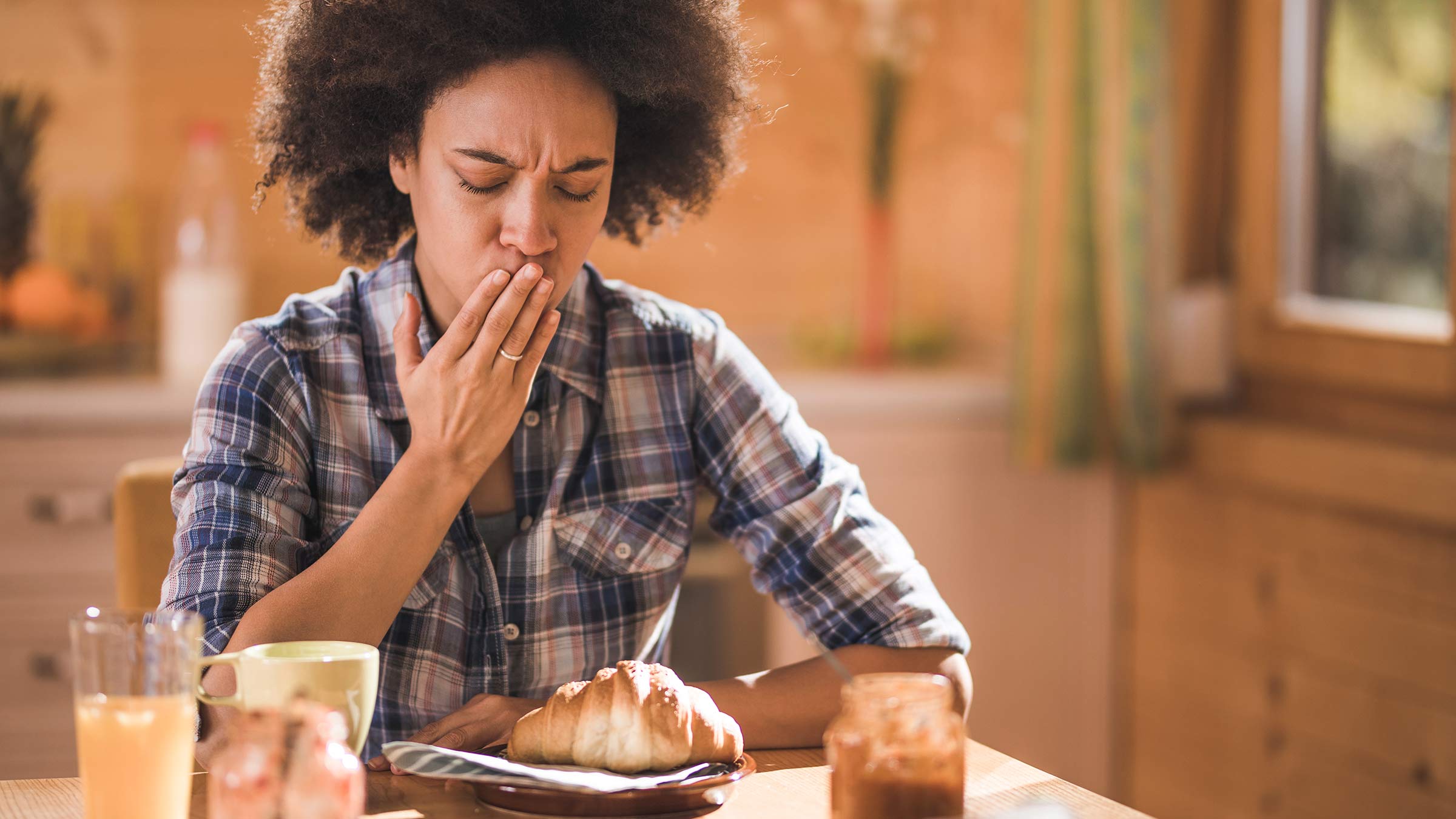 A woman feeling nauseous during breakfast