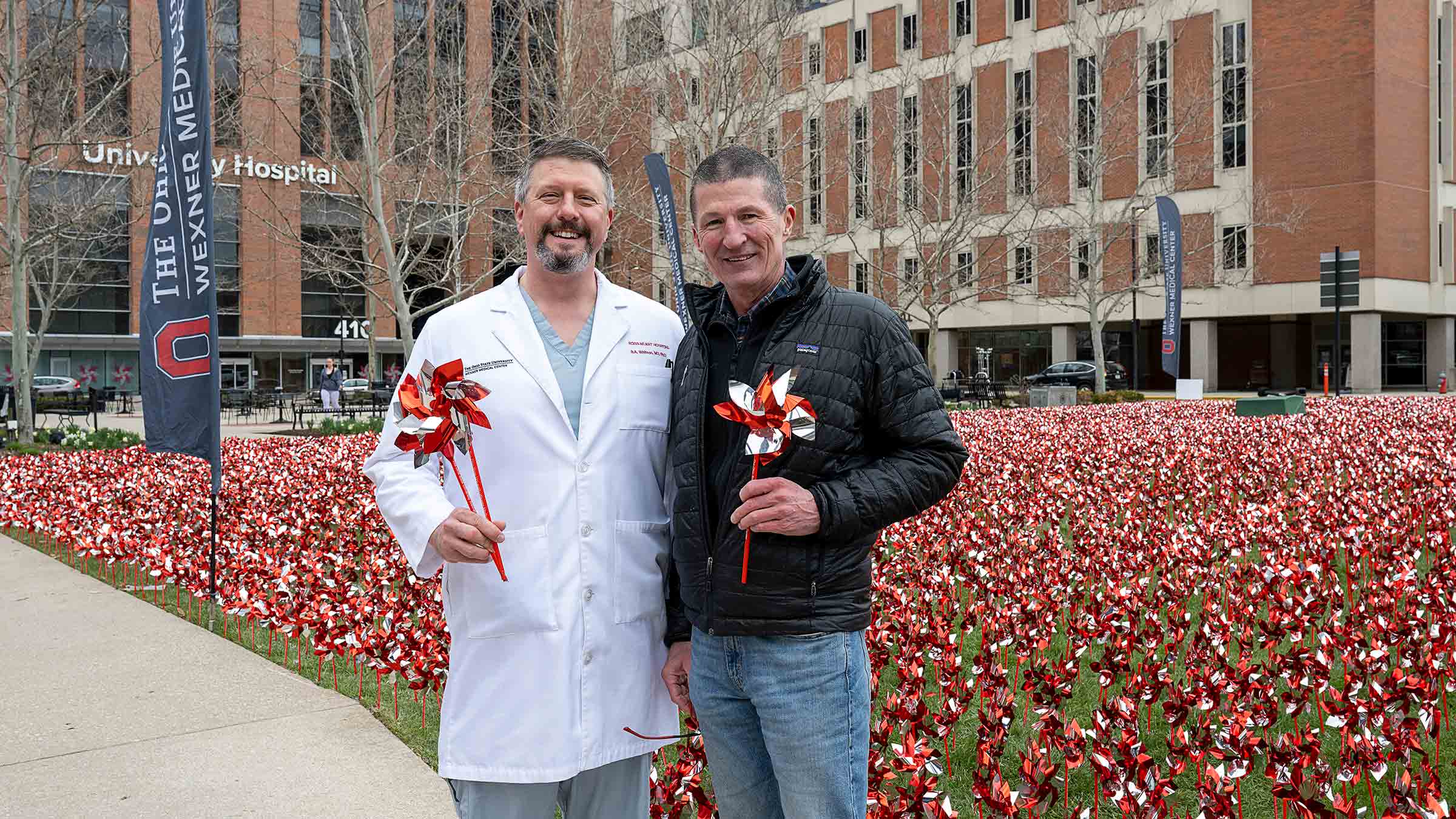 Dr. Whitson with Dr. Washburn in front of the lawn full of red pinwheels