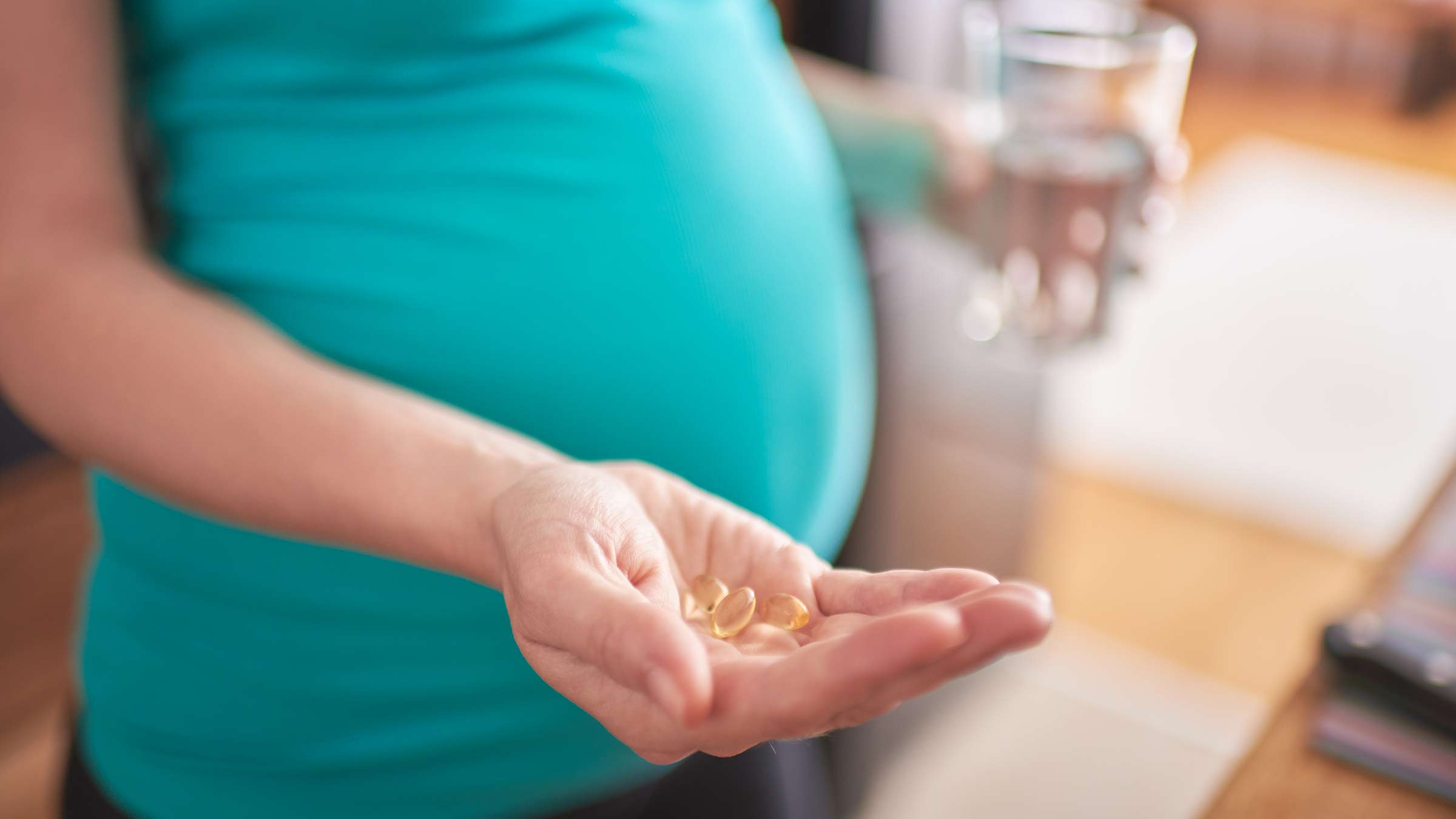 A pregnant woman holding prenatal vitamins