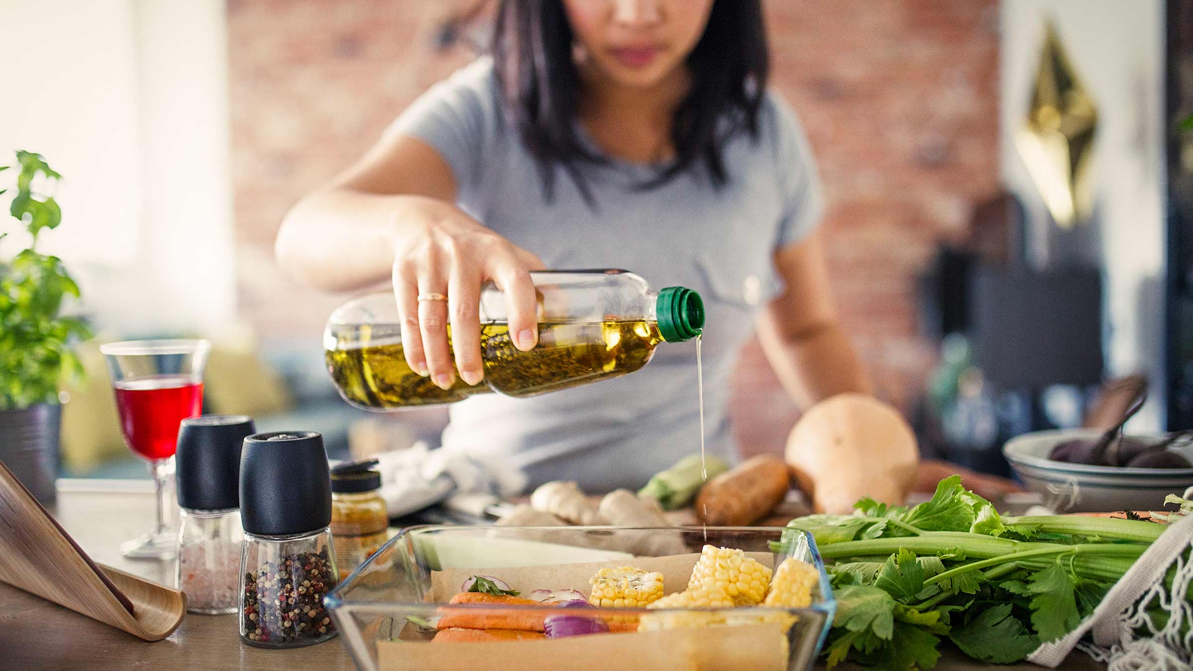 A woman pouring cooking oil into a baking dish