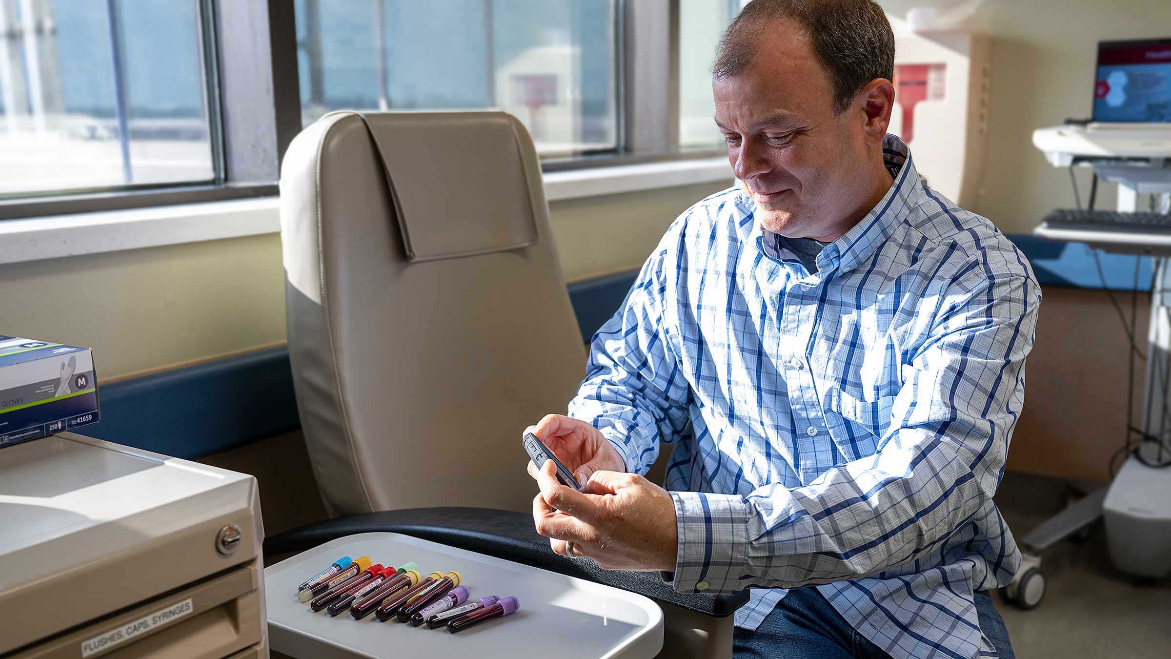 Mike in a lab with blood collection tubes on the tray in front of him
