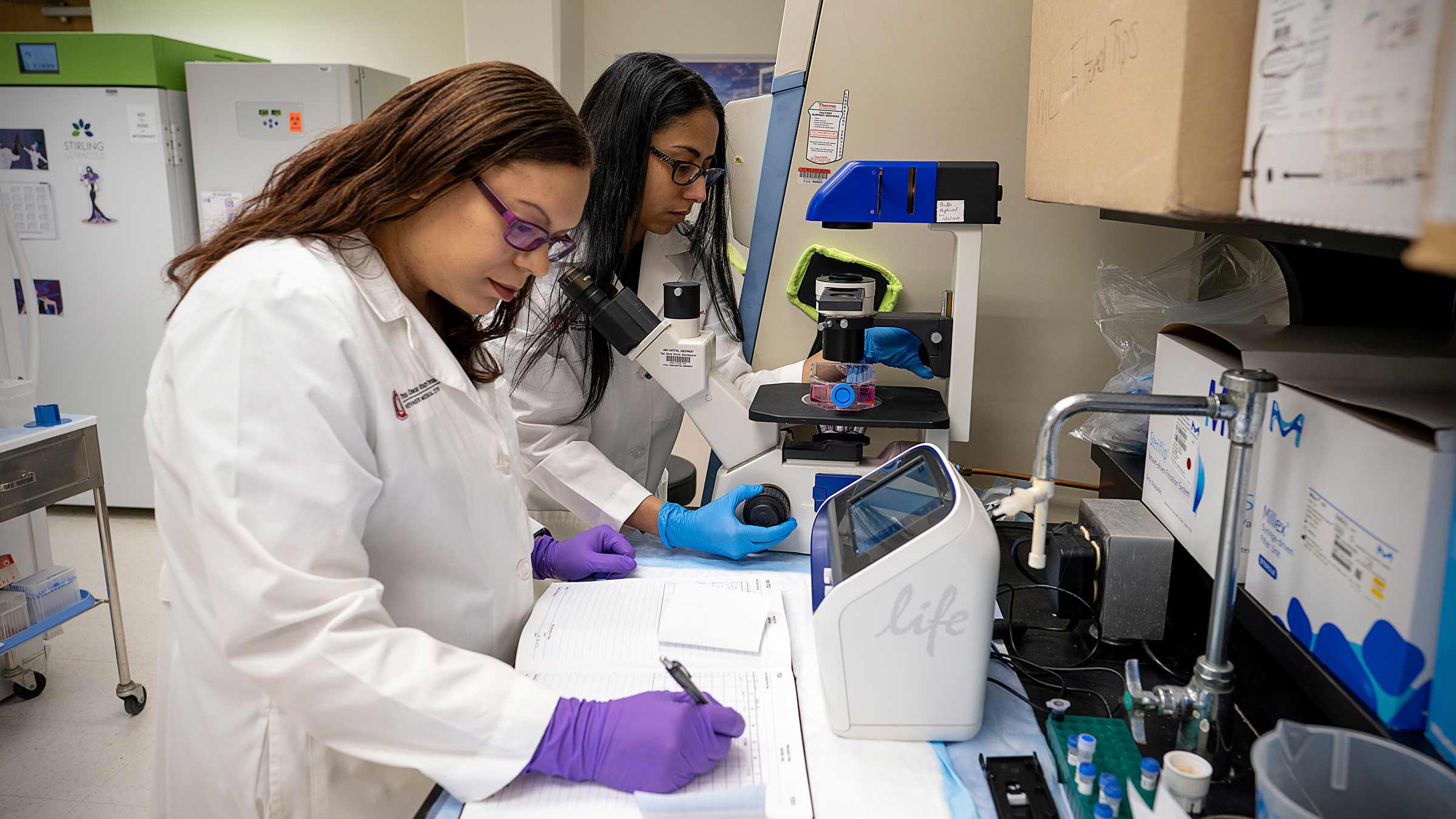 Dr. Cruz-Monserrate with a colleague in the lab writing down the results
