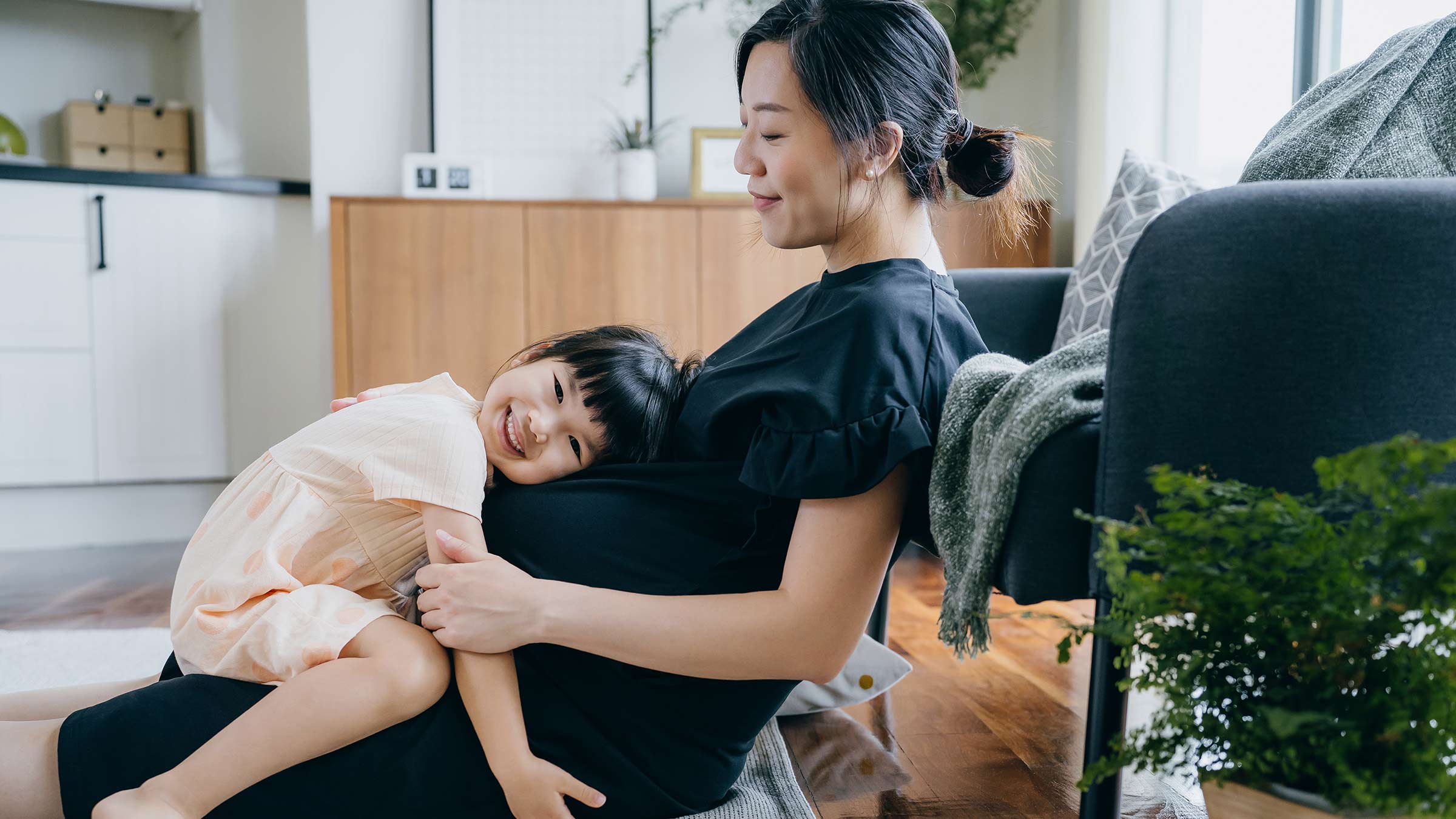 Little girl lying on her mother's pregnant belly