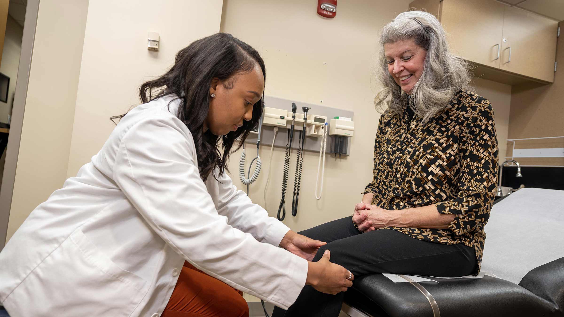 First year medical student examines a patient's knee