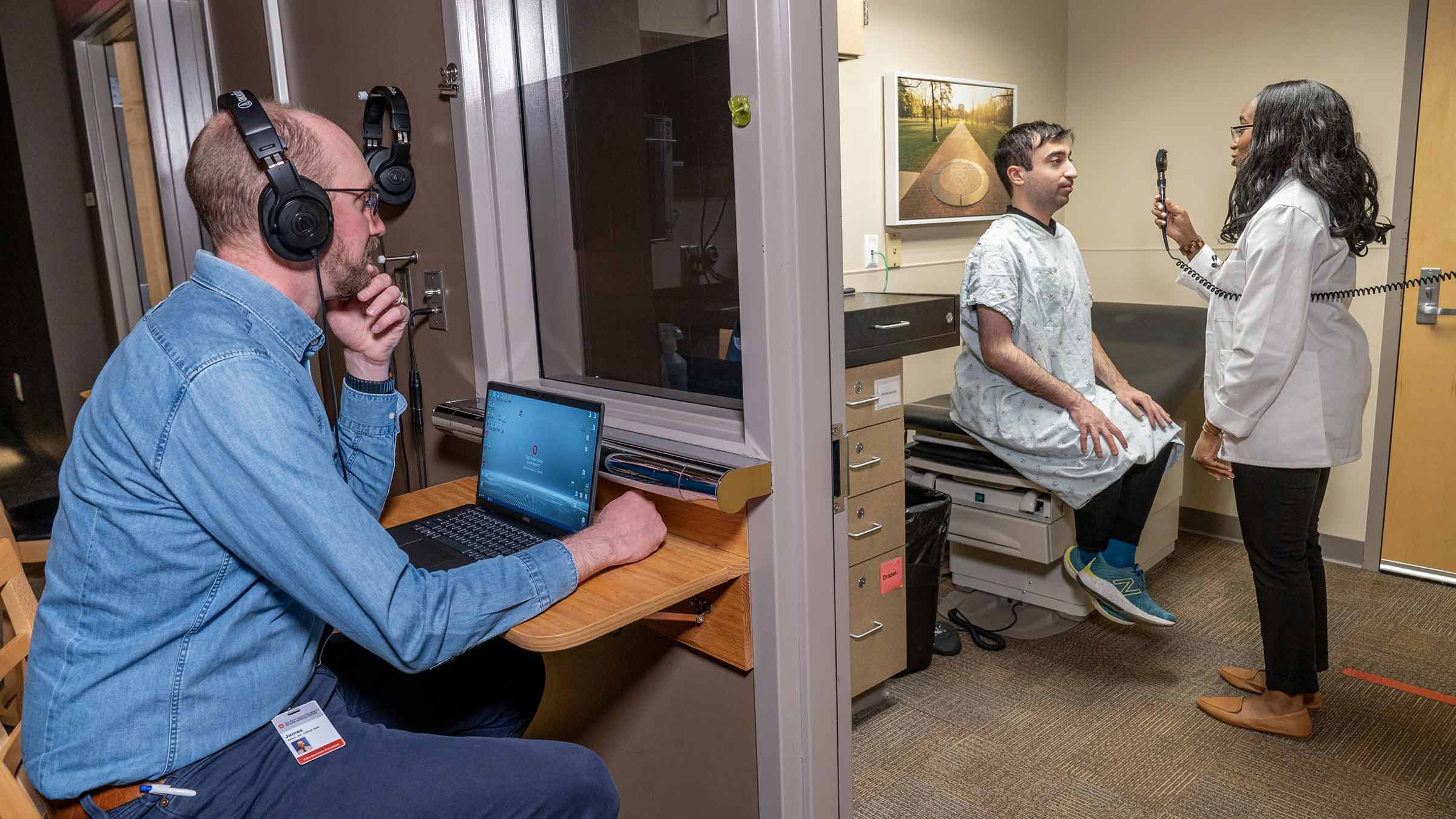 Medical student sees a mock patient at the Clinical Skills Education and Assessment Center, while being observed by a trainer