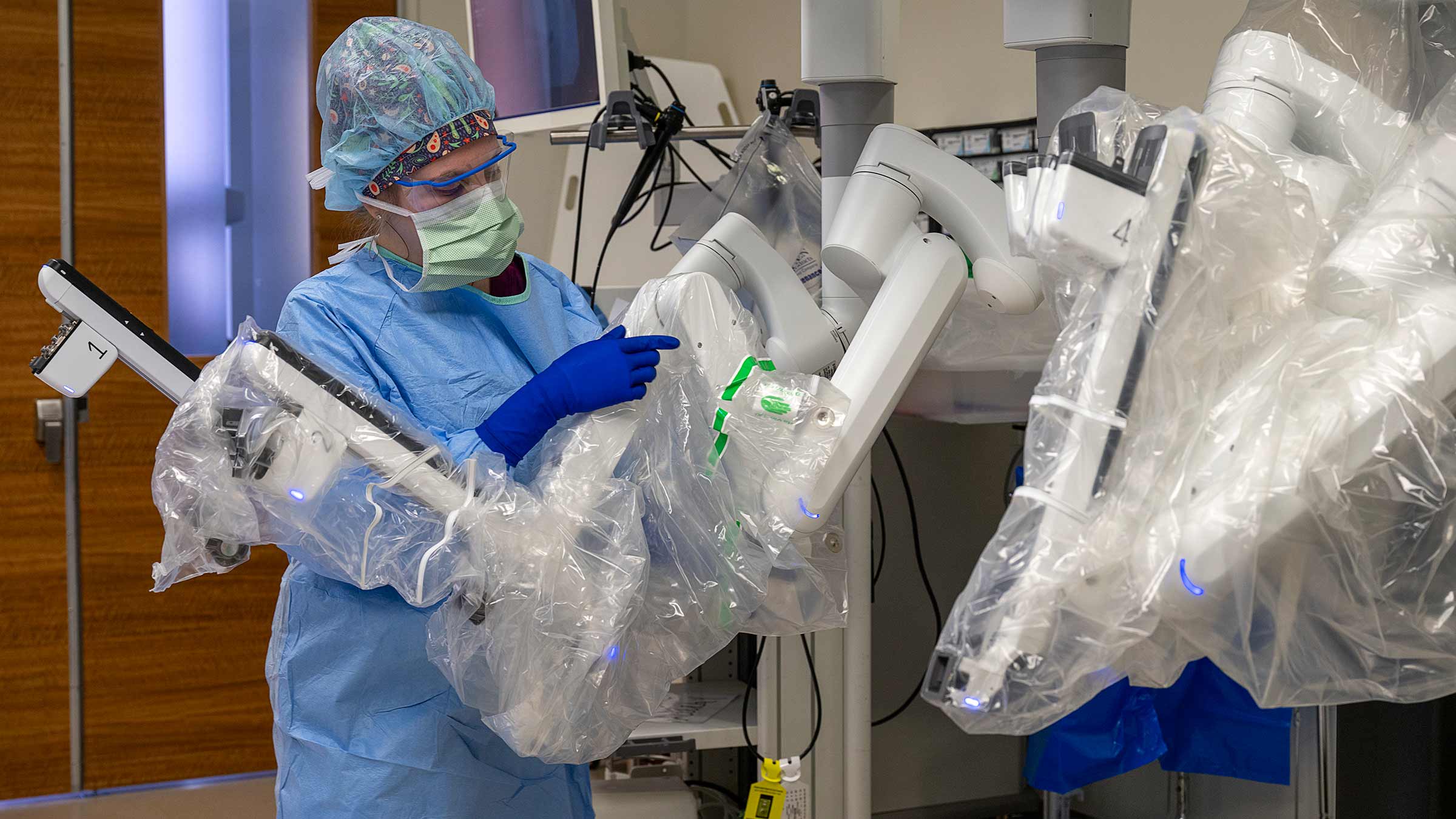 A surgical tech covering the da Vinci 5 machine’s arms in surgical plastic