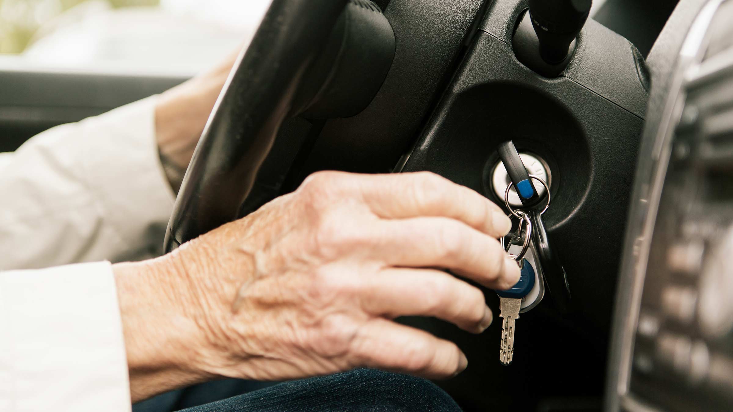 Close up image of senior woman putting car key in ignition