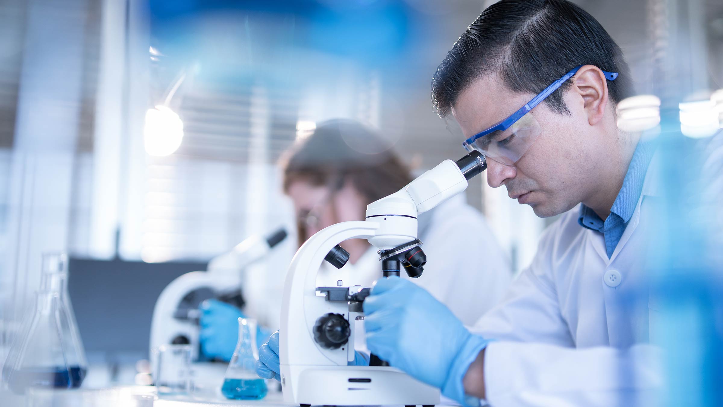 Two laboratory technicians looking through microscopes