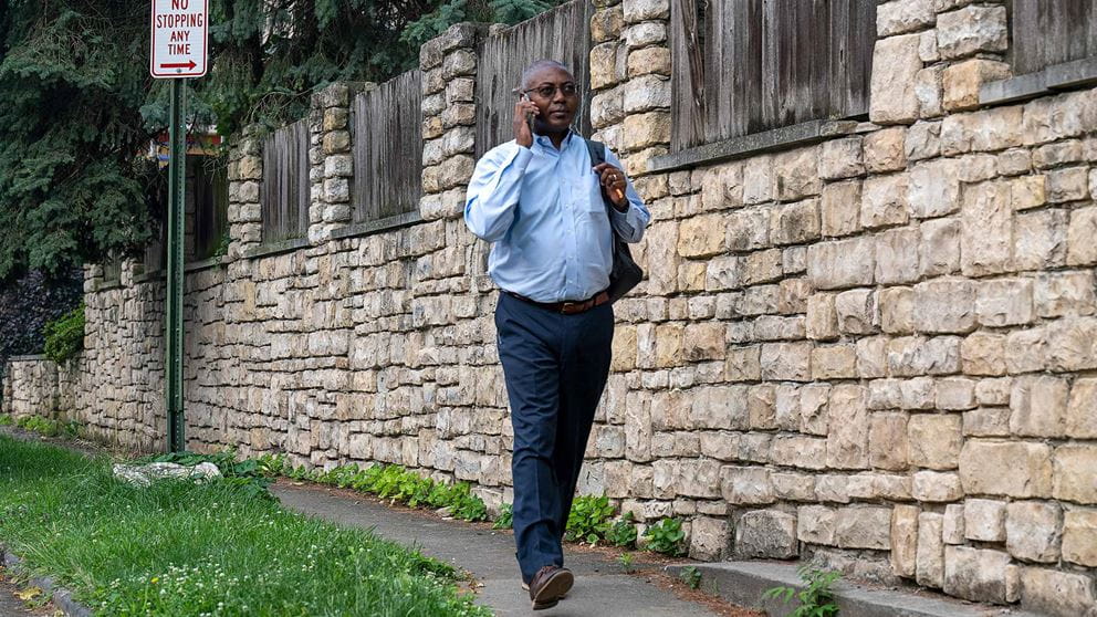 Dr. Doubeni walking on the street talking on a phone