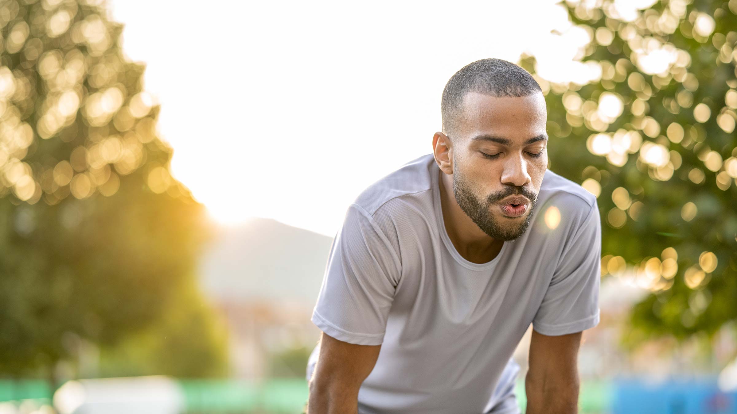 Young Black man bending over with hands on knees, breathing deeply after outdoor training